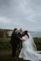 Bride and groom during the ceremony of their elopement in Ireland, doing the hand-fasting tradition