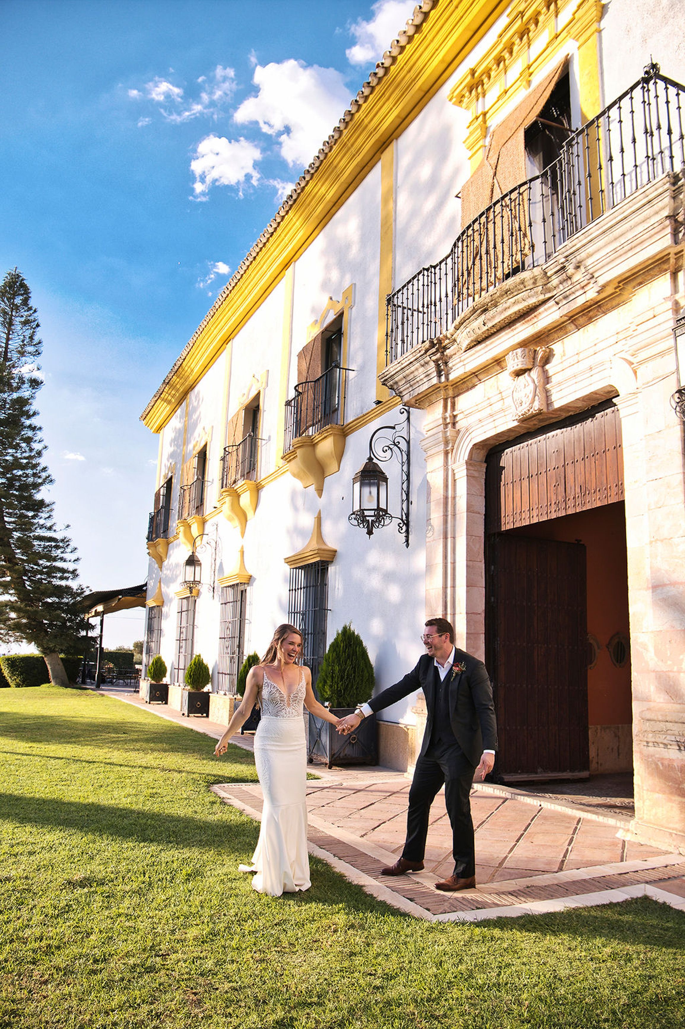 Bride and groom walking hand in hand outside a historic estate during an intimate wedding in Europe