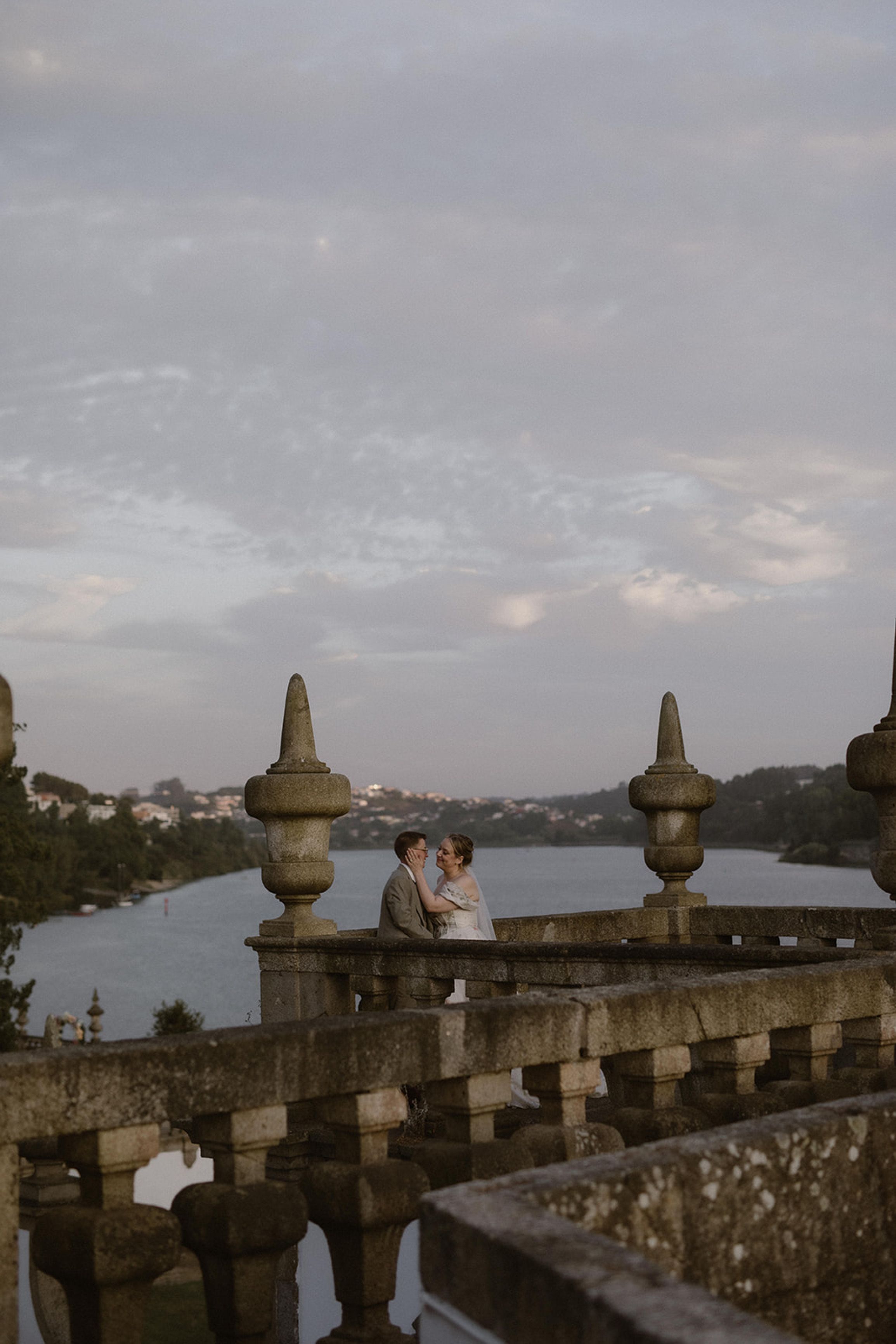 Newlyweds embracing on a grand riverside terrace at an intimate wedding in Portugal