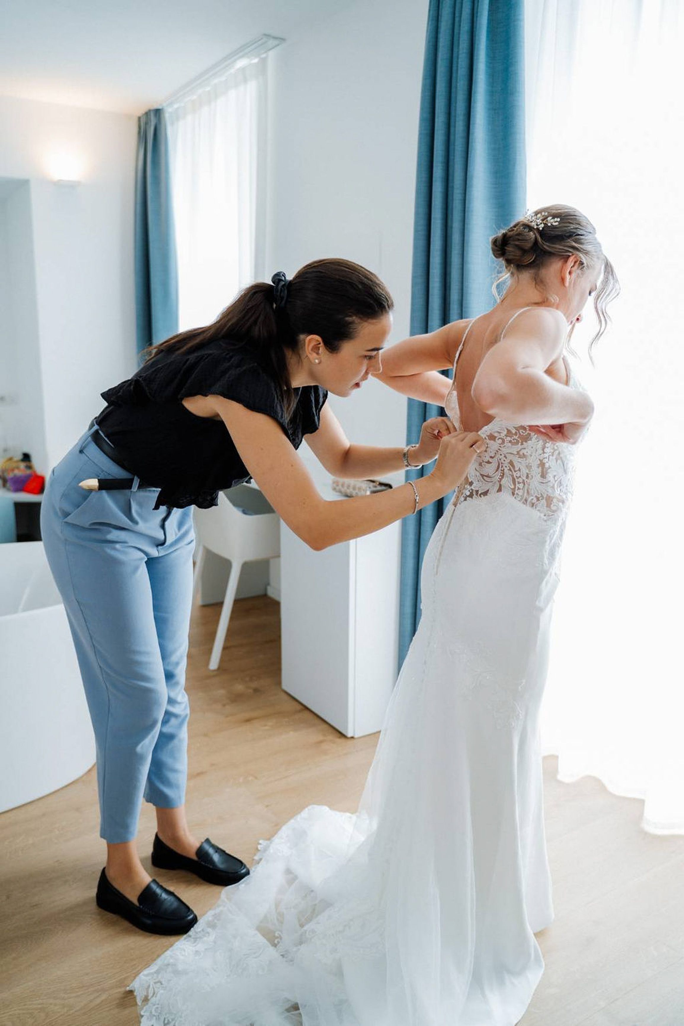 Planner fastening the bride's lace wedding dress before an intimate wedding in Europe