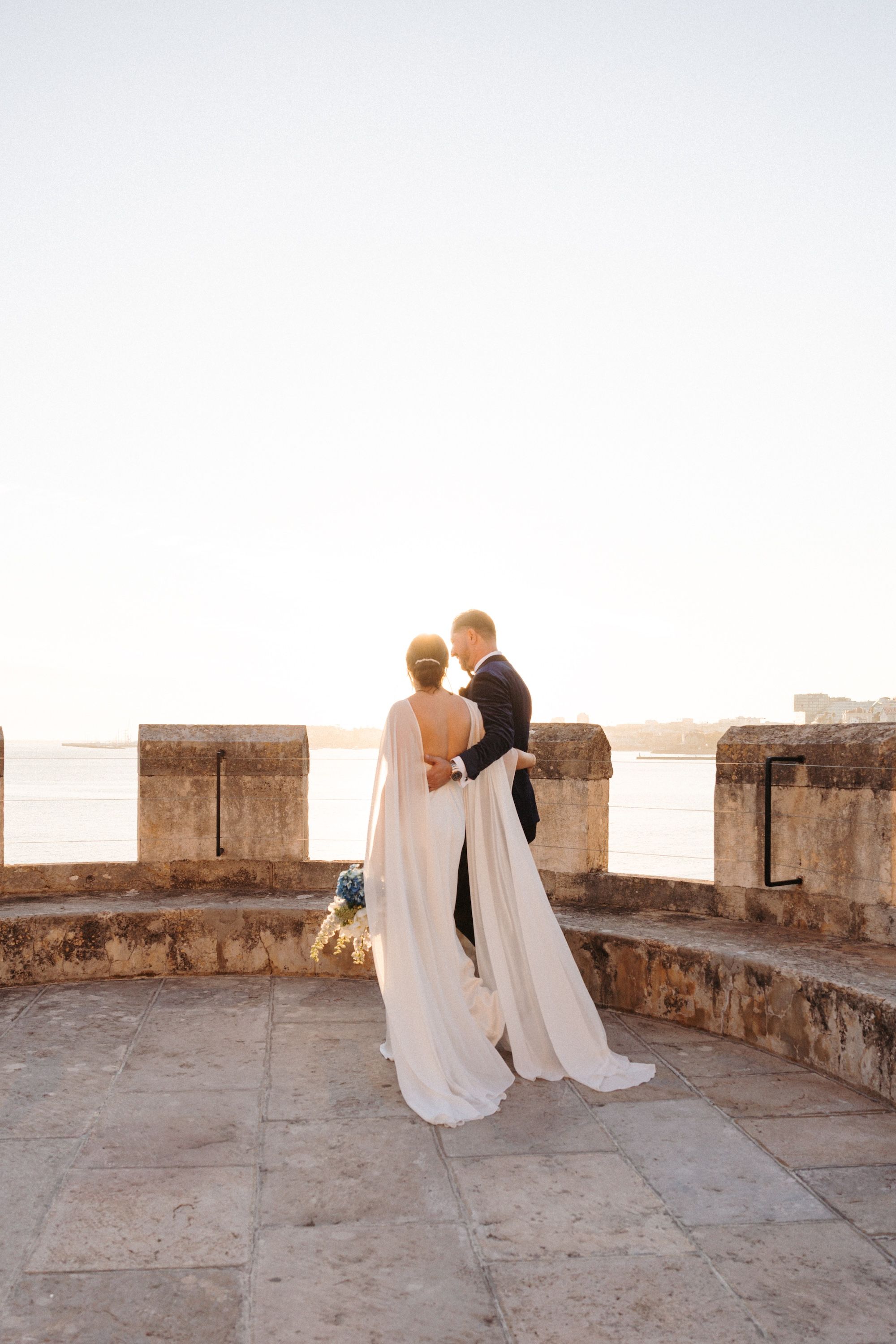 Newlyweds walking around the castle turret where they had a micro wedding in Portugal