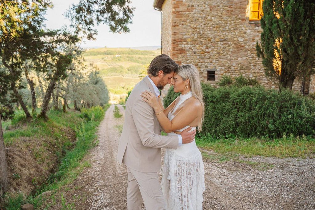 Bride and groom having a photoshoot for their small wedding in Italy with a Tuscan farmhouse in the background