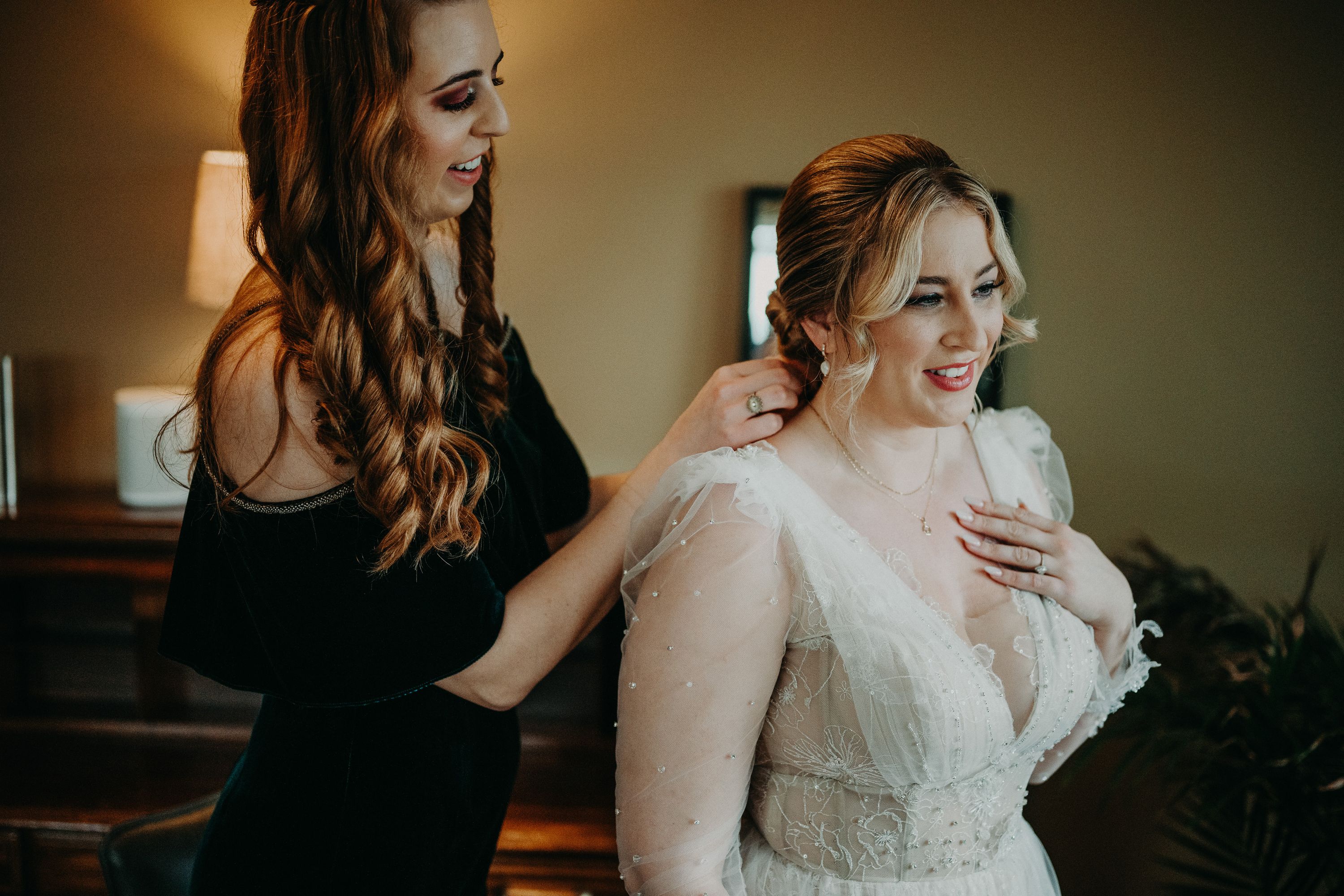 A bride having her necklace by her sister in preparation for her intimate wedding in Ireland