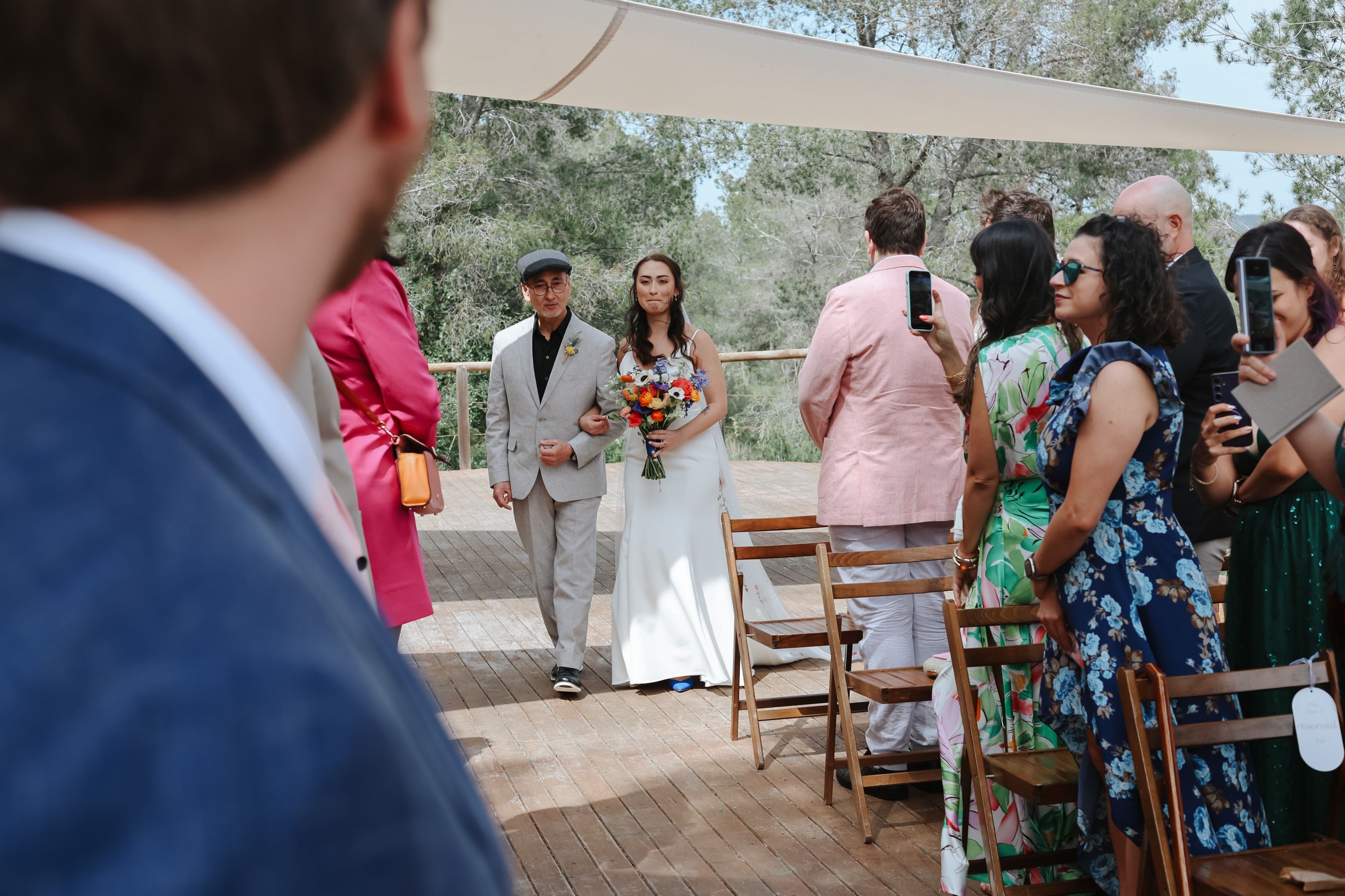 Bride walks down the aisle with a man while groom and guests watch in Spain