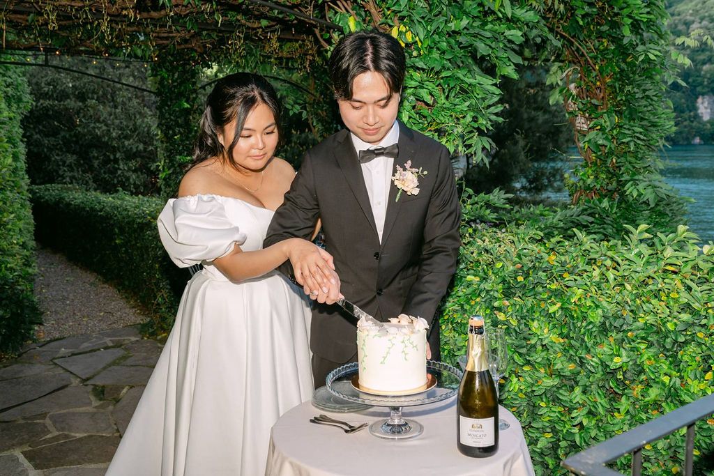 Newlyweds slicing a cake in the garden during the intimate dinner of their elopement in Italy