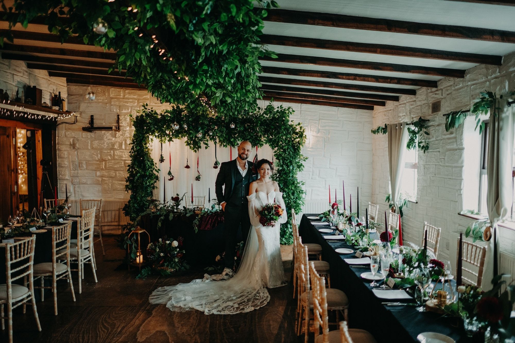 Bride and groom pose in the middle a their rustic, nature-themed pub venue during their small wedding in Ireland