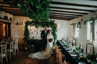 Bride and groom pose in the middle a their rustic, nature-themed pub venue during their small wedding in Ireland
