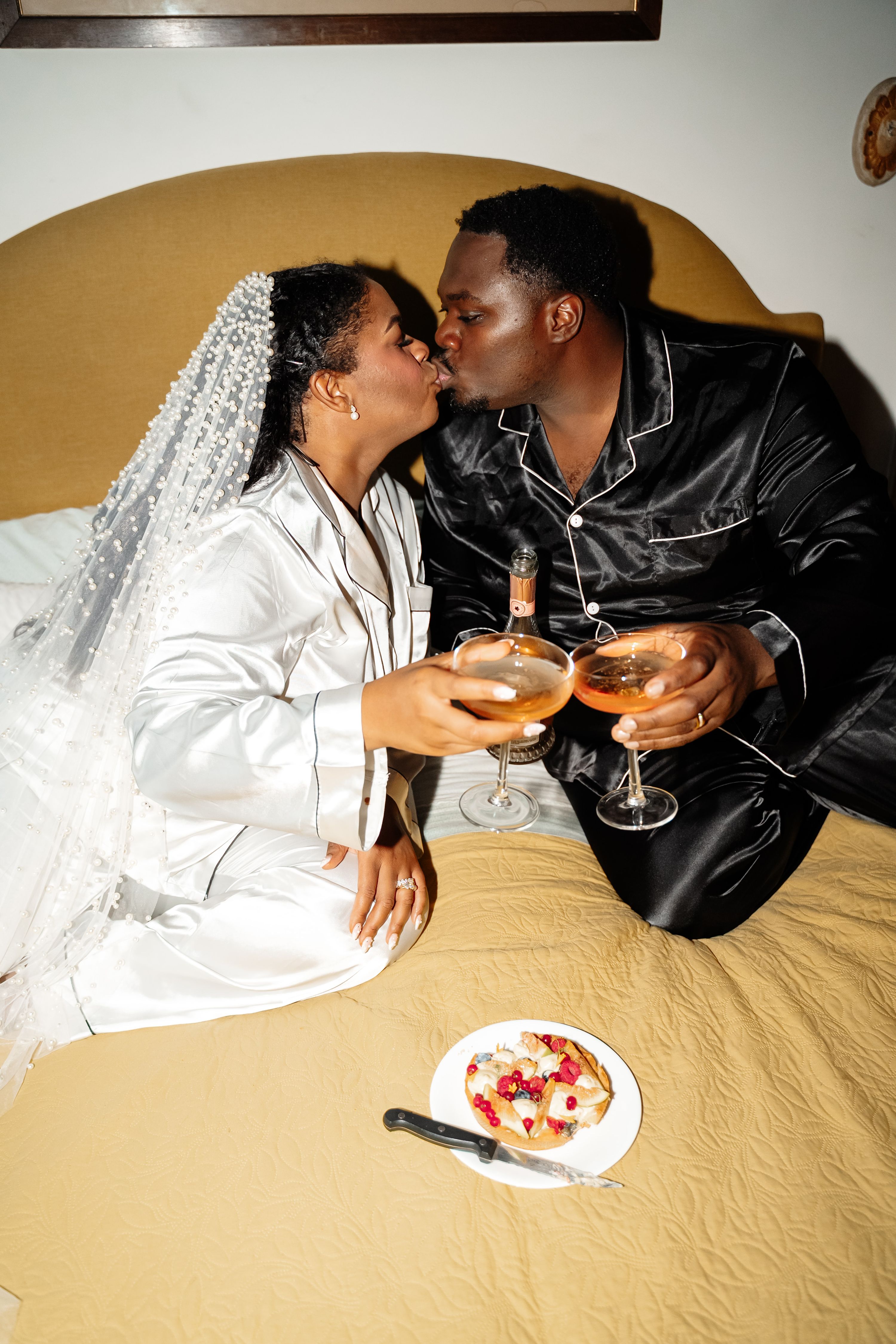 Newlyweds kissing while holding wine glasses in an Airbnb room after their elopement in Italy