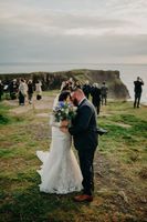 Bride and groom kiss on top of the cliffs during the ceremony of their micro wedding in Ireland