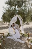 Bride and groom kiss under a simple floral and cloth wedding arch during their outdoor micro wedding in Portugal