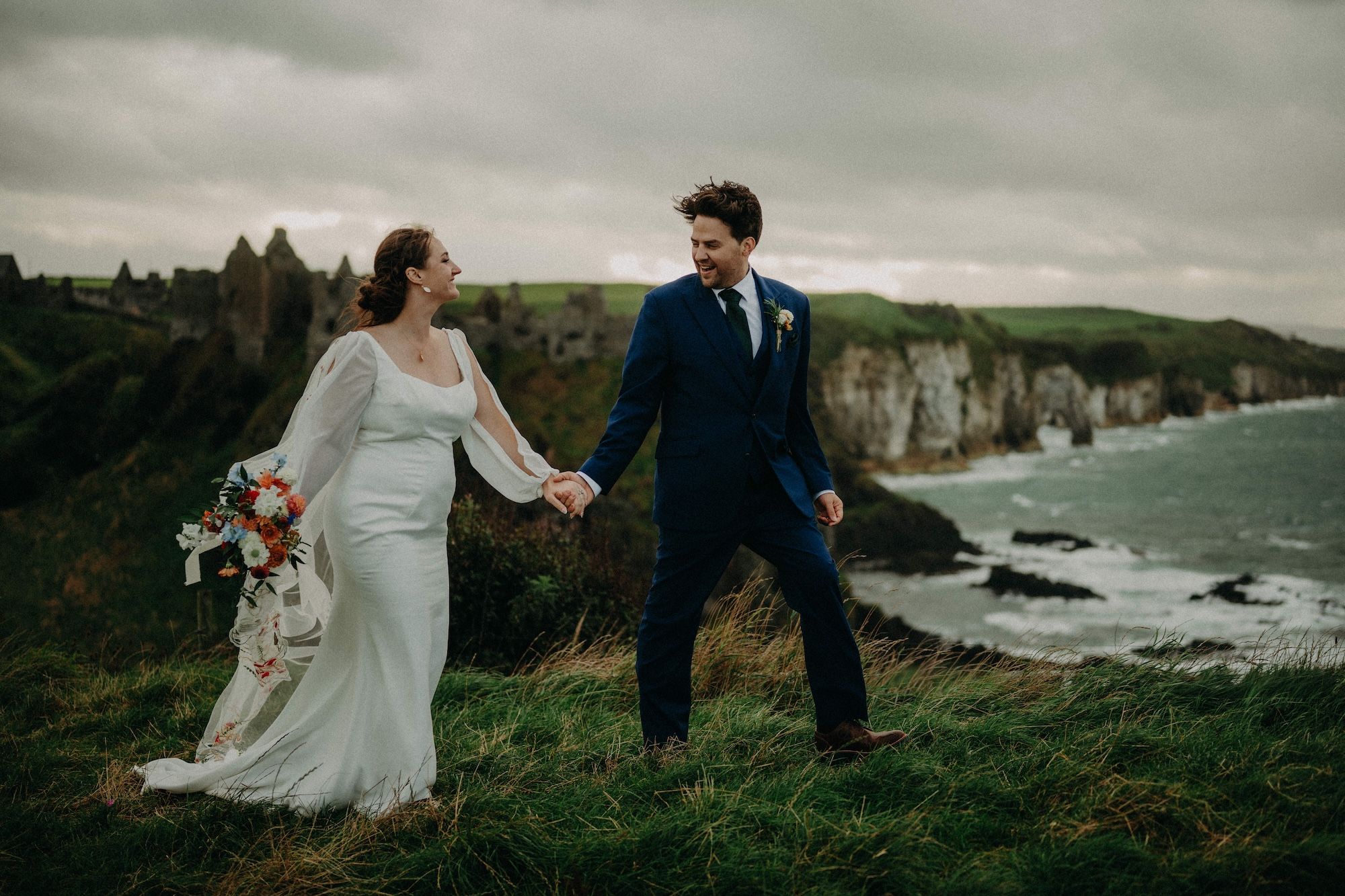Bride and groom walking on the clifftop meadows of Antrim during their micro destination wedding in Ireland.