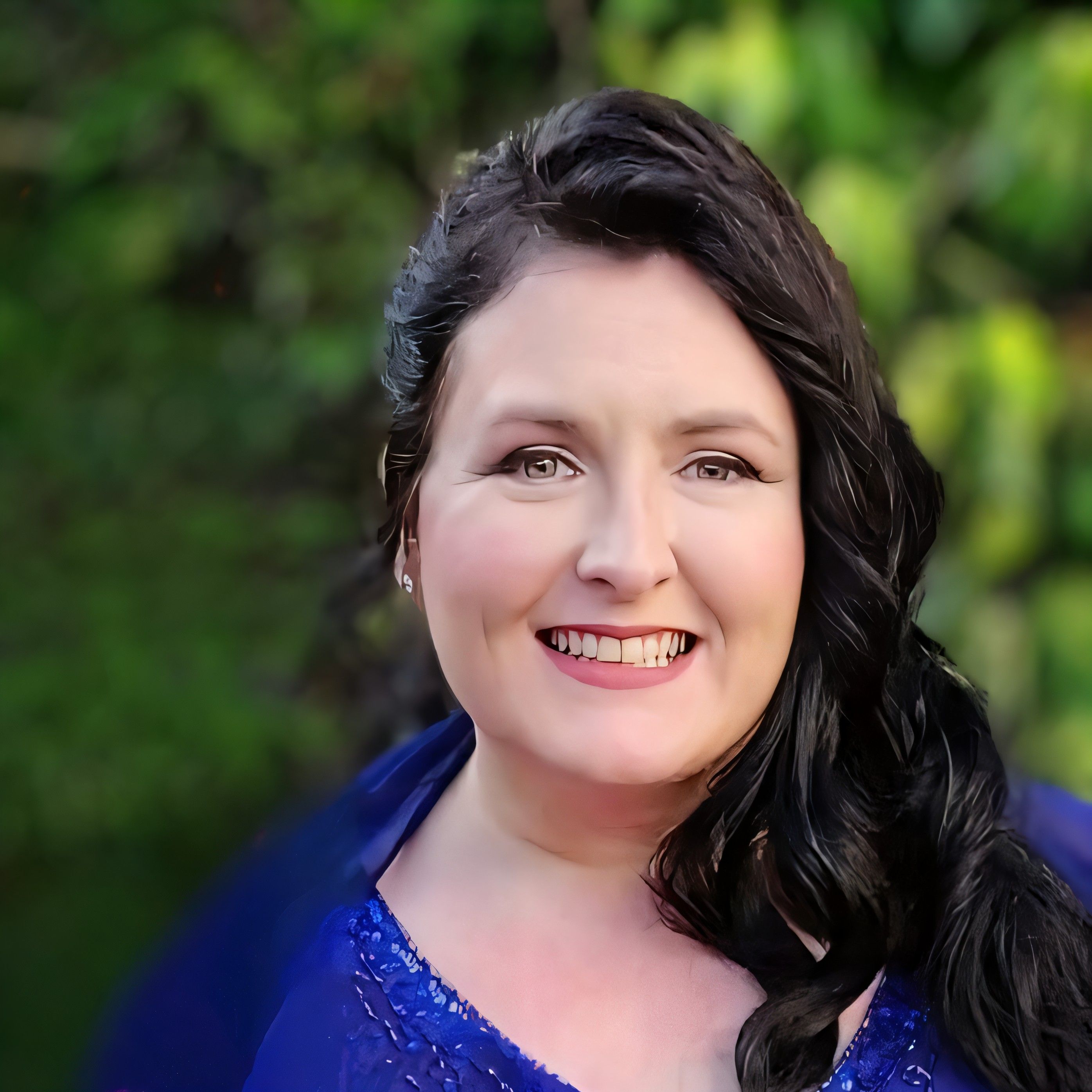 Our wedding planner in Northern Ireland wearing a blue top with a forest background