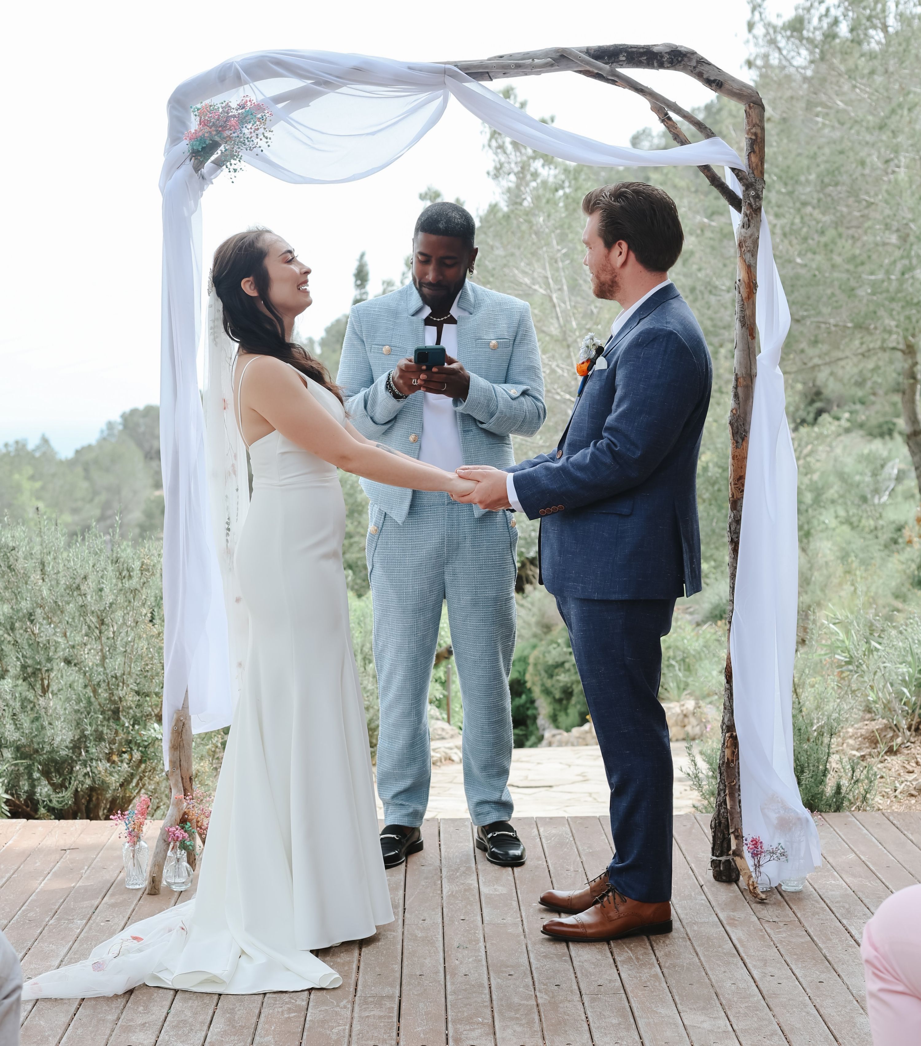 Bride and groom holding each other in front of their celebrant during the ceremony of their destination wedding in Spain