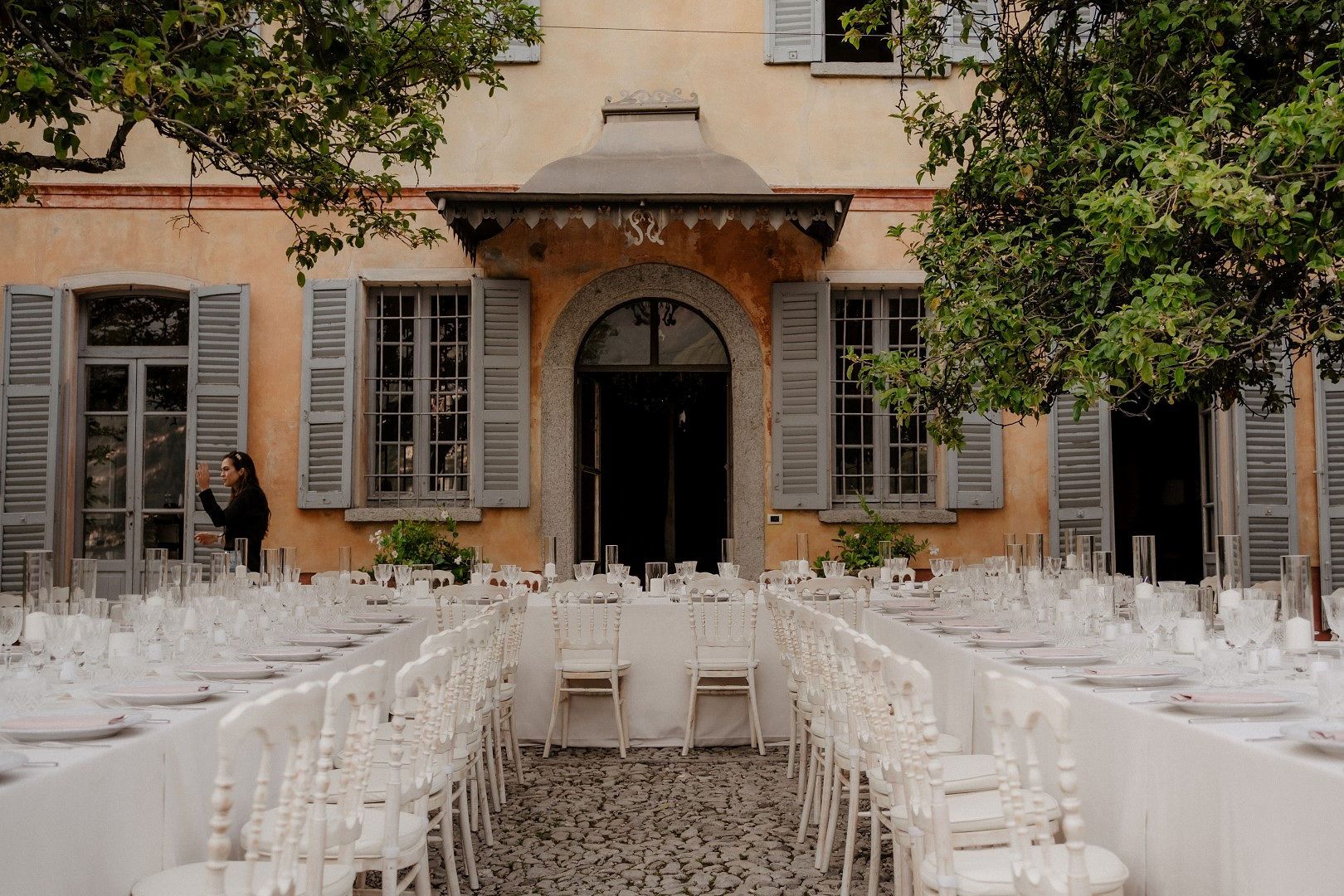 An elegant and historic looking villa with tables and chairs arranged for a dinner of a destination wedding in Italy