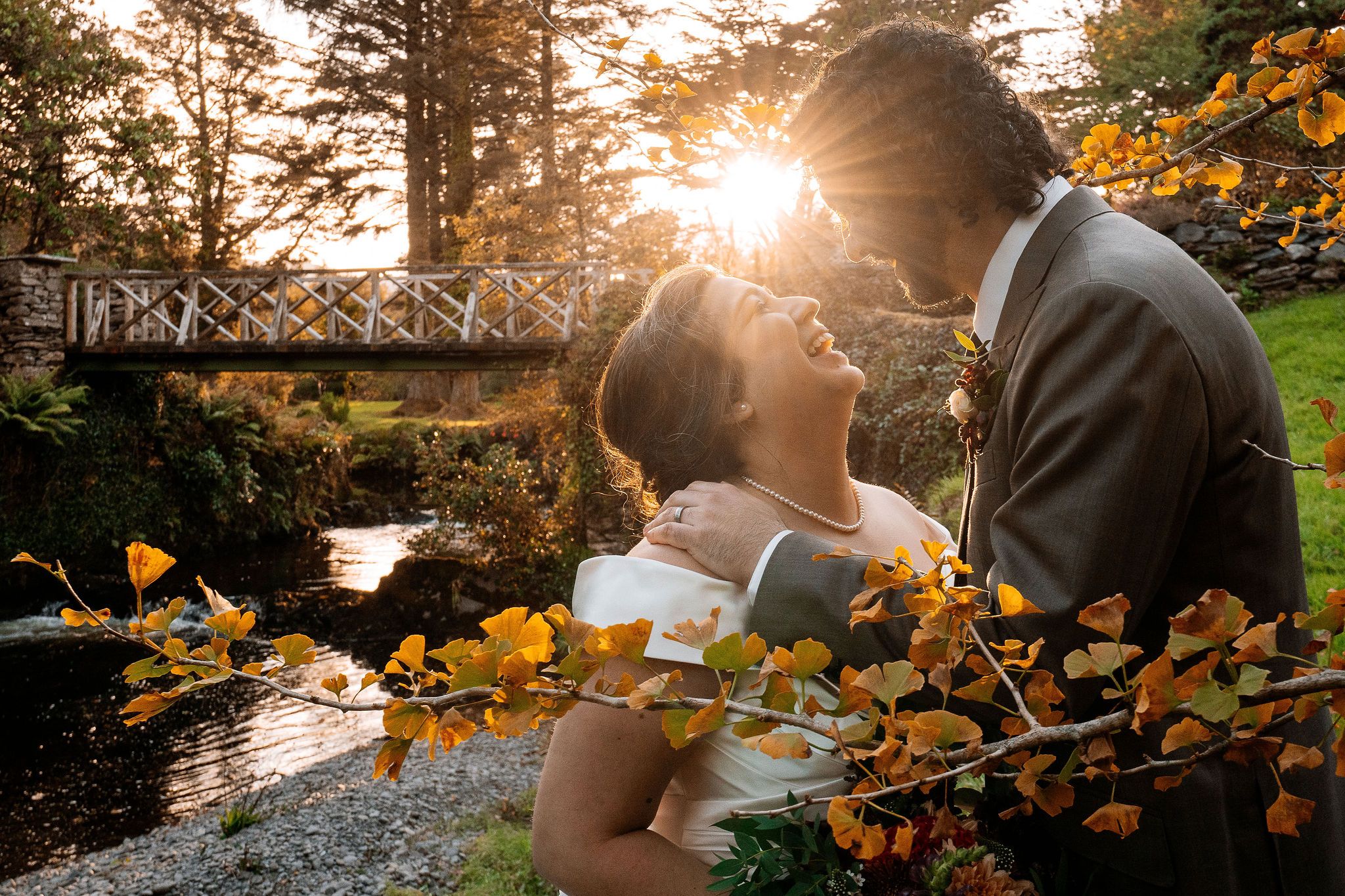 Bride and groom kissing with the sunset and the autumn woodland behind them during their elopement in Ireland