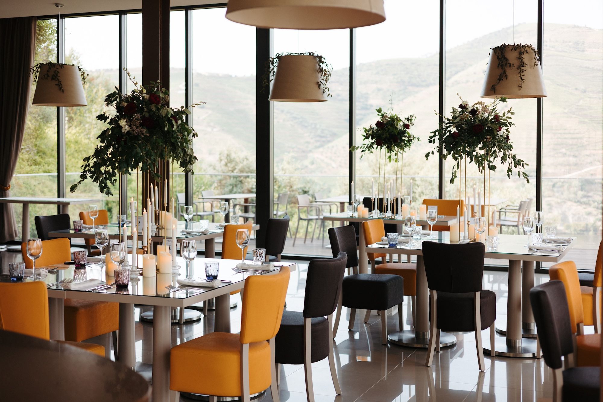 A glass-walled reception area overlooking the Douro region's mountains, arranged for a small wedding in Portugal