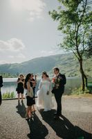 Bride and groom talk to guests outdoors with lake and mountains in the background during their micro wedding in Ireland