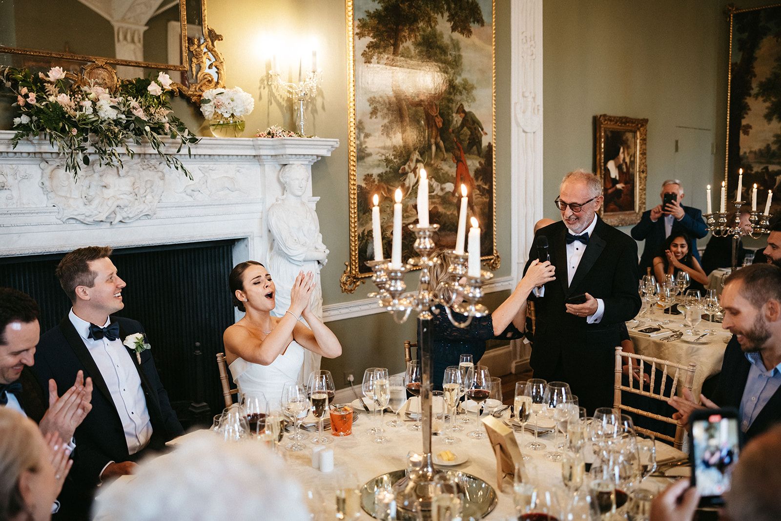 Bride and groom clap as someone from their guests gives a speech during their small wedding in Ireland