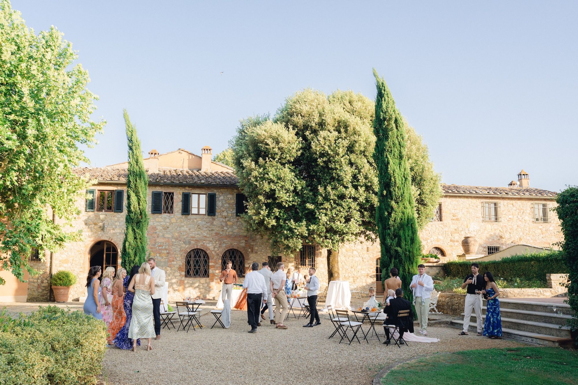 Guests having a drinks reception in the middle of a courtyard of a villa in Tuscany during a destination wedding in Italy