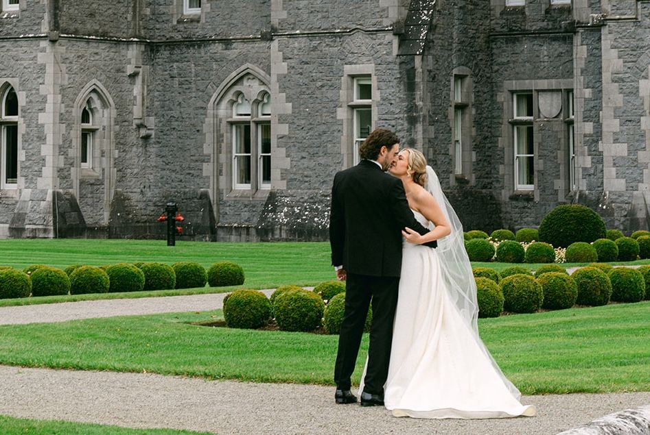 Bride and groom kissing in front of a medieval castle in Mayo, Ireland