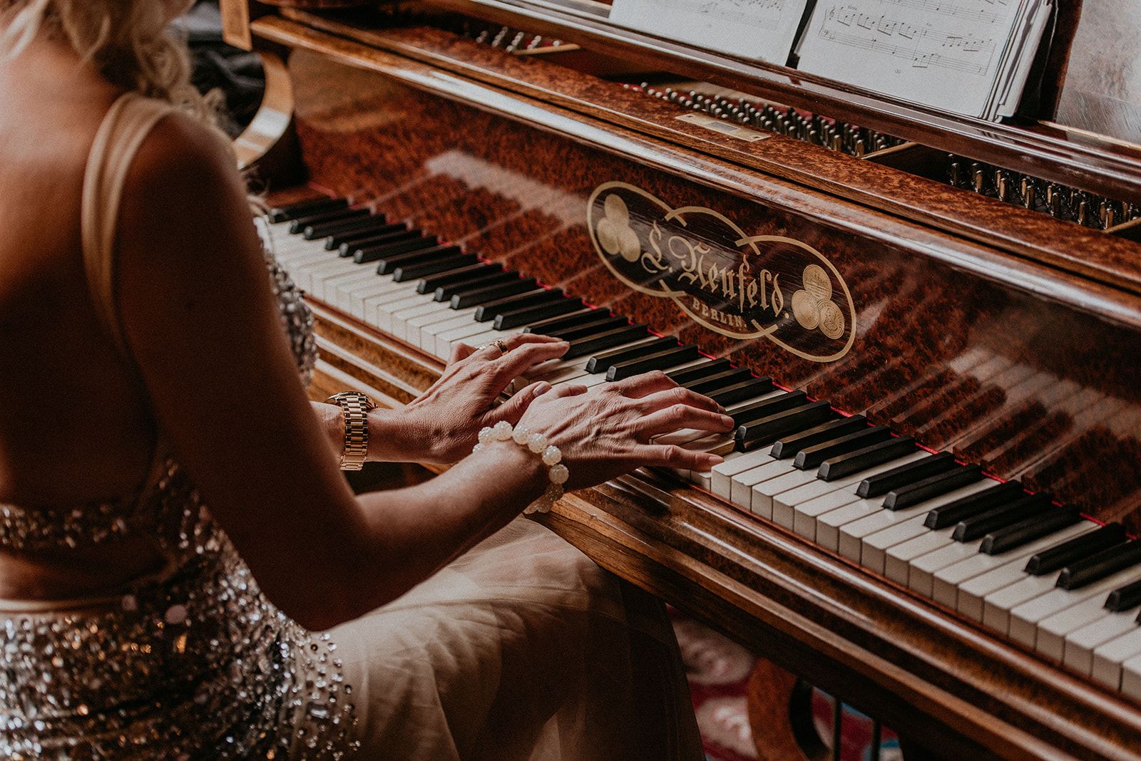 Bride playing an antique grand piano in her wedding dress