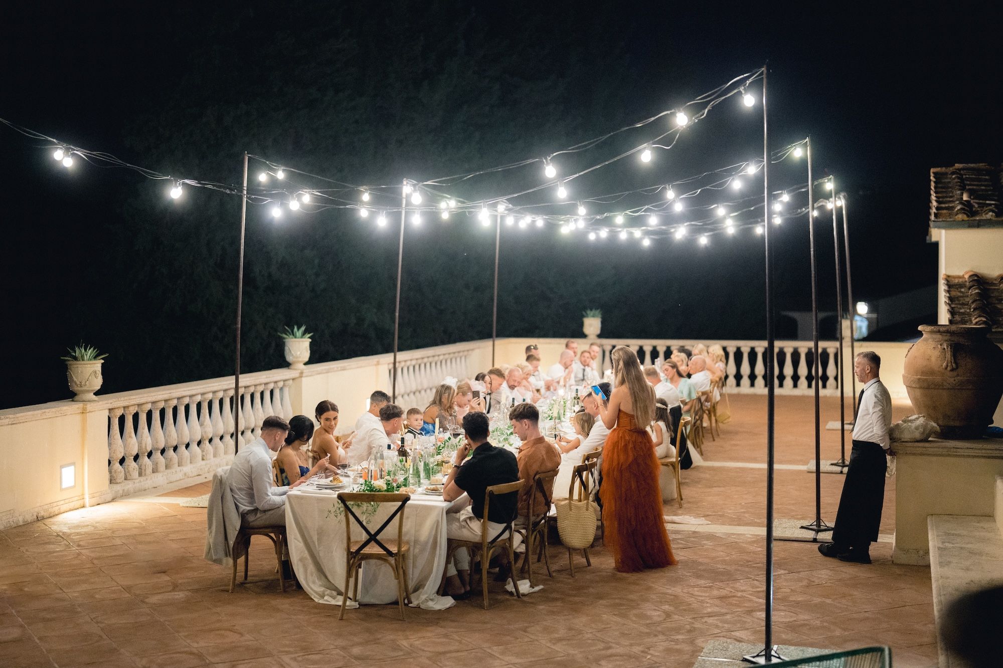 A whole wedding party under the night sky and fairy lights in Tuscany having a wedding reception in Italy