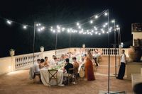 A whole wedding party under the night sky and fairy lights in Tuscany having a wedding reception in Italy