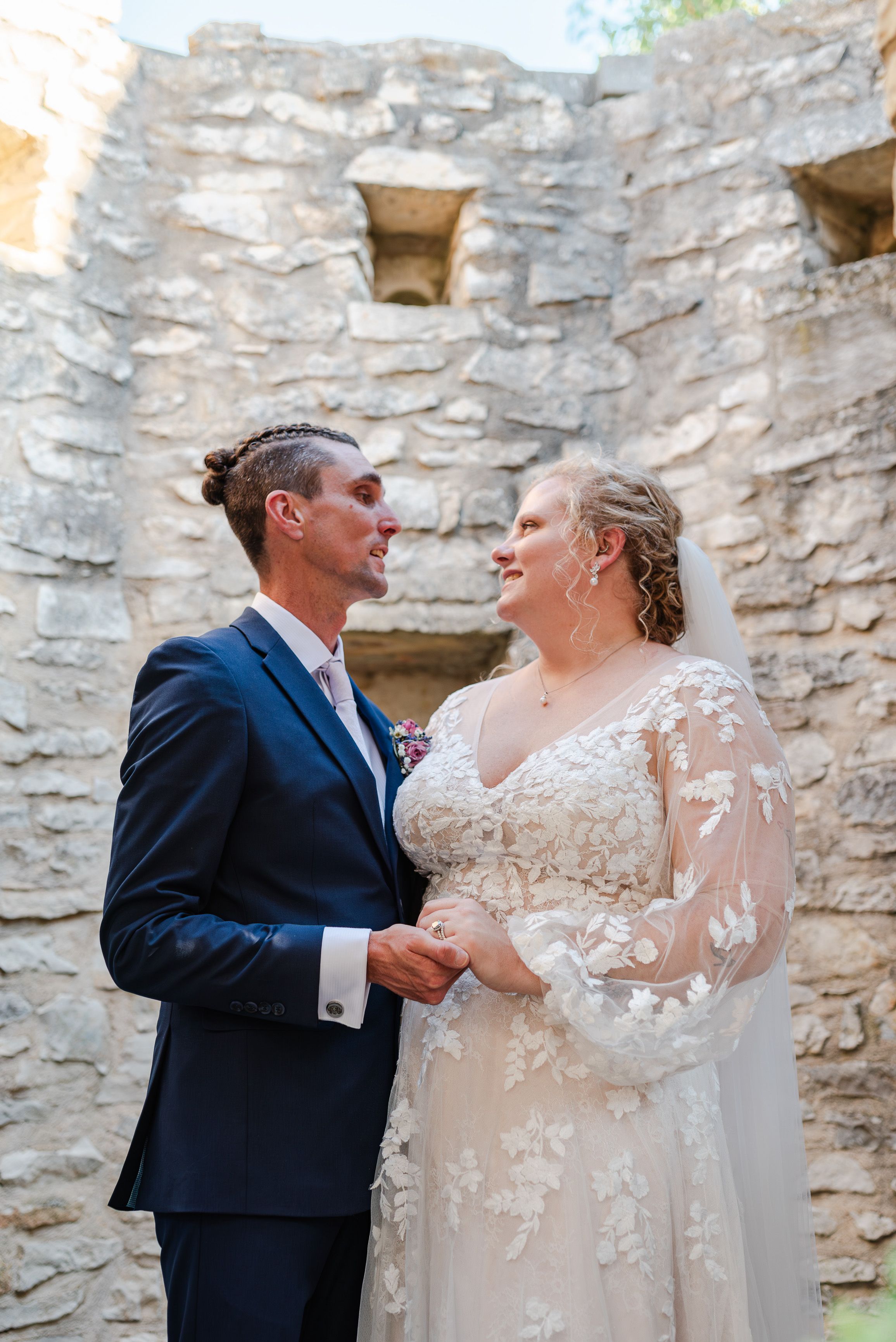 Bride and groom sharing a quiet moment beside historic stone ruins at an intimate wedding in France