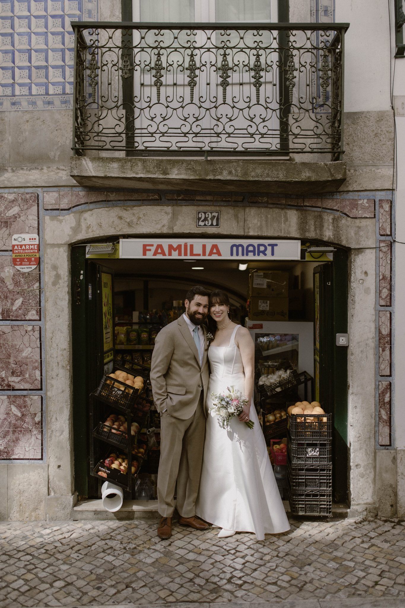 Bride and groom kiss in front of an iconic building in Lisbon during the photoshoot of their micro wedding in Portugal