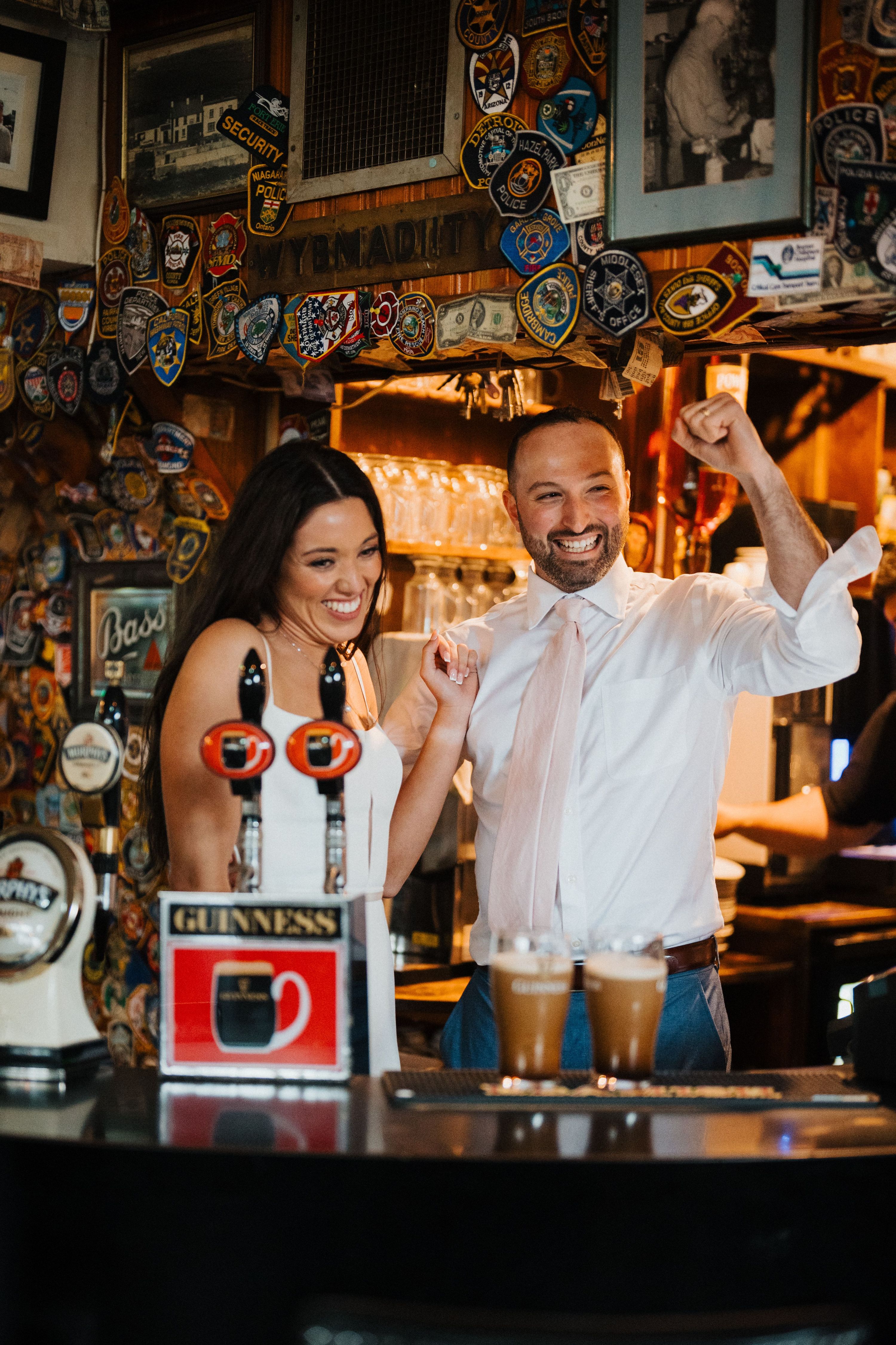 Bride and groom celebrating inside a traditional Irish pub while drinking Guinness beer.