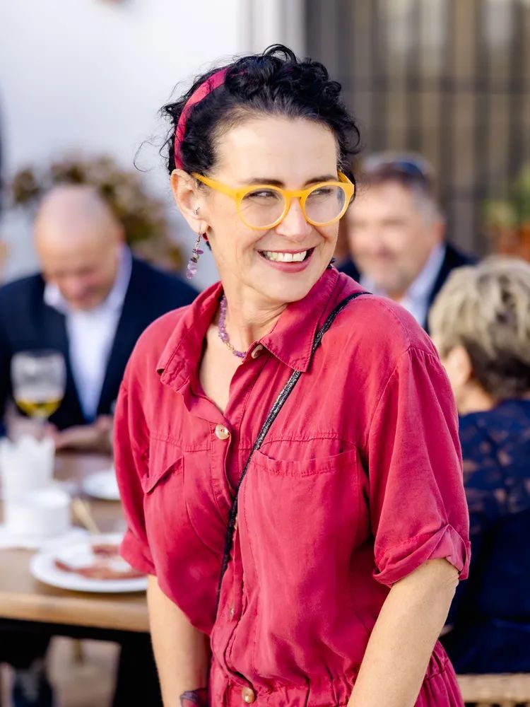 Wedding planner in Spain in a red shirt and glasses, smiling with people at the back during a destination wedding in Spain