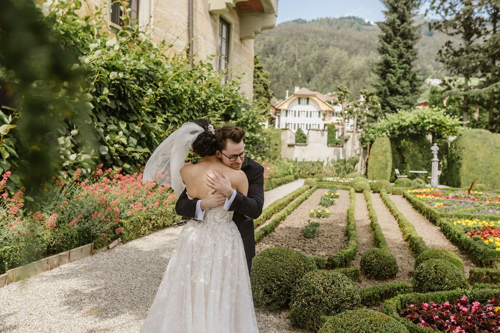 A groom hugging his wife in a beautiful garden before their small wedding