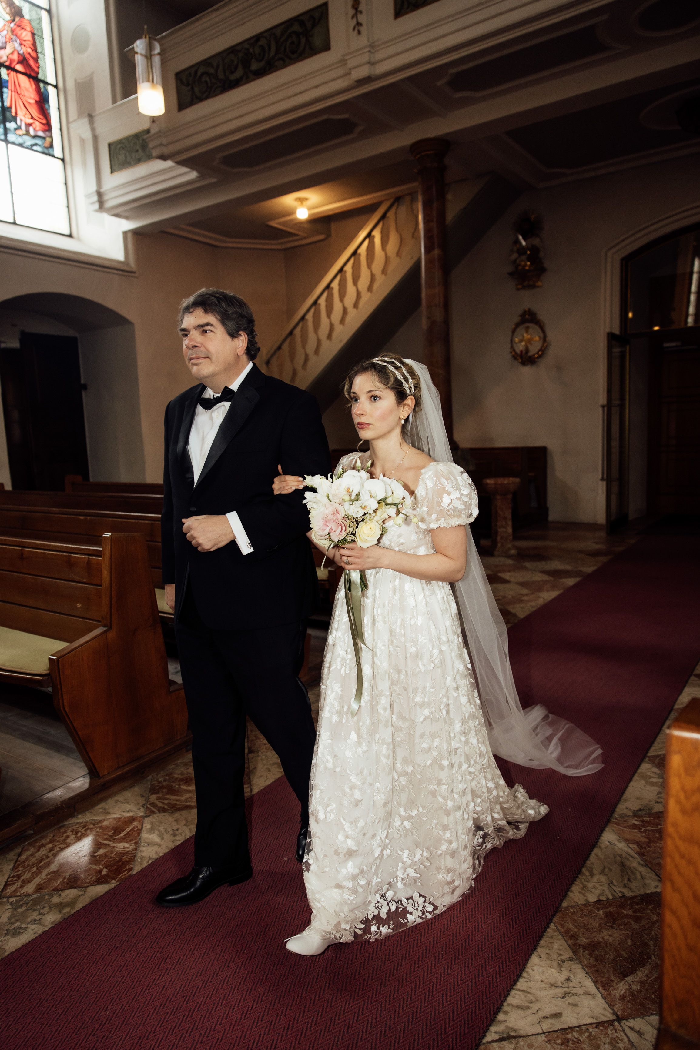 Bride walks arm in arm with her father during an intimate wedding in Austria church ceremony