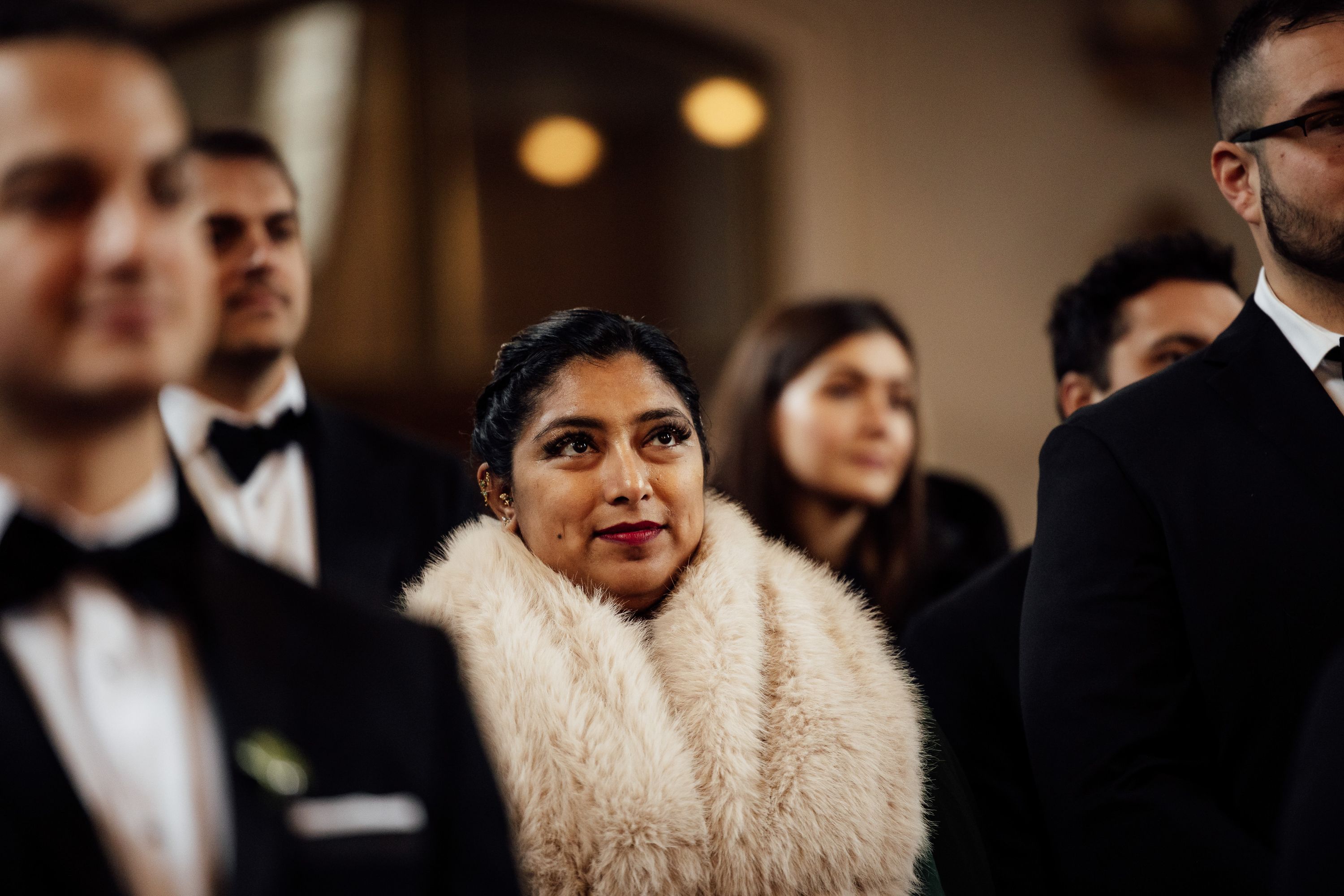 Guest wearing a fur shawl listens during an intimate wedding in Austria ceremony