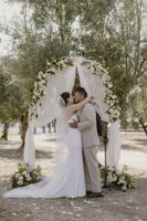 Bride and groom kisses in the middle of a simple floral and cloth wedding arch during a micro wedding in Portugal