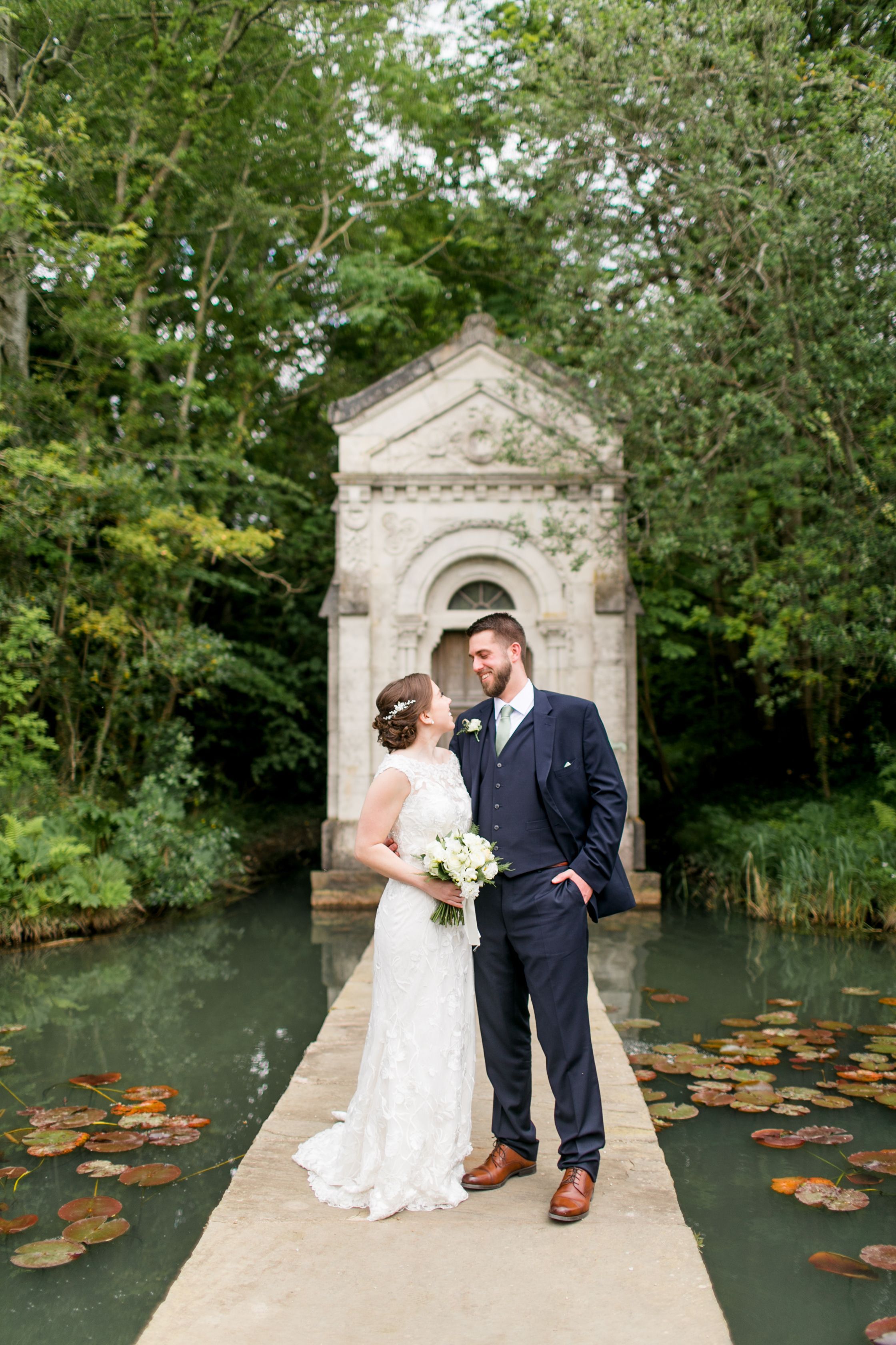Newlyweds look at each other while on a platform in the middle of a pond where they had a destination wedding in Ireland