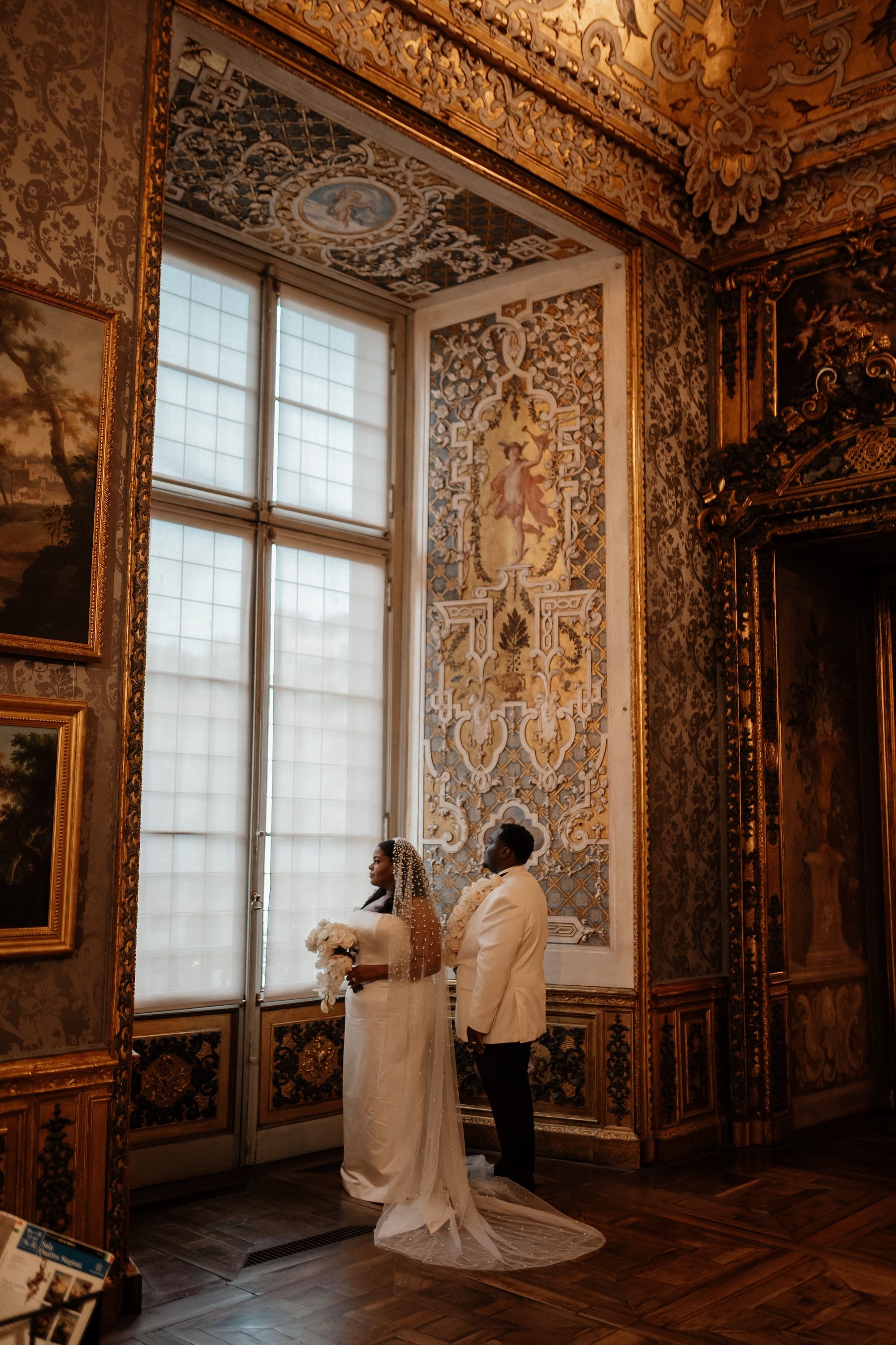 Bride and groom looking outside of the large window of the museum in Turin where they eloped in Italy