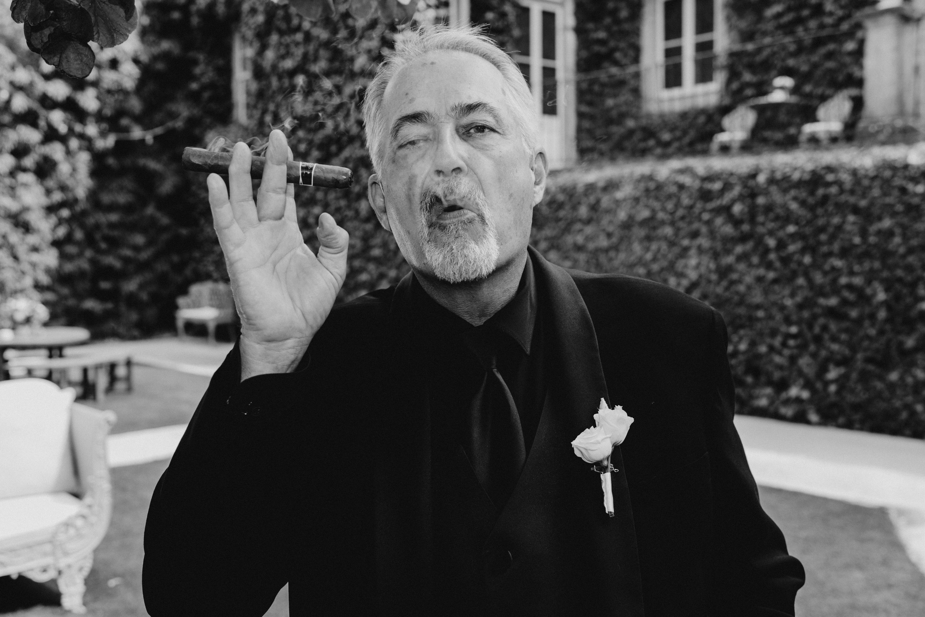 the stylish father of the bride enjoying a cigar in black and white