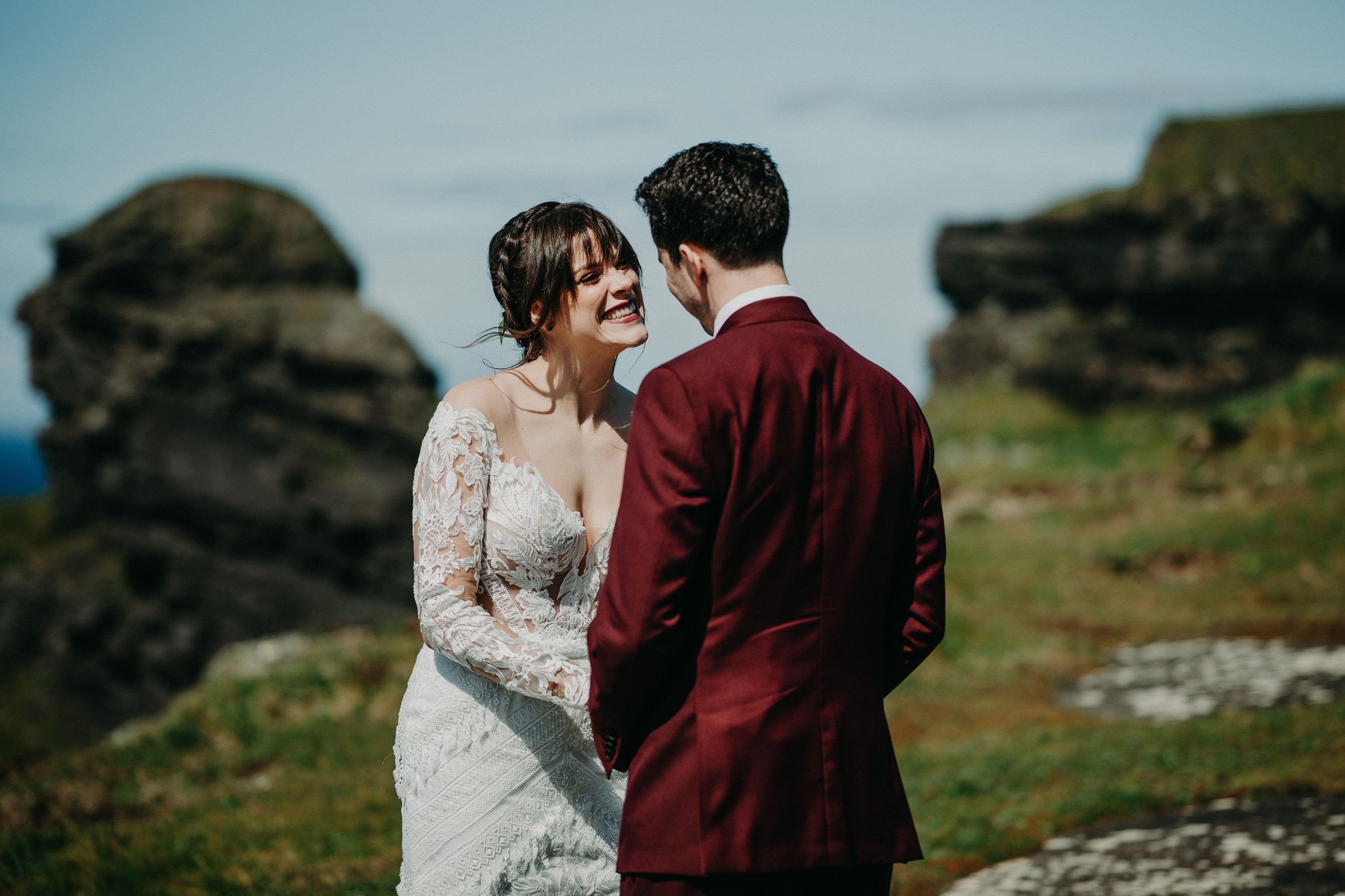 A bride gazing lovingly at her groom on top of a cliff during their small wedding in Ireland