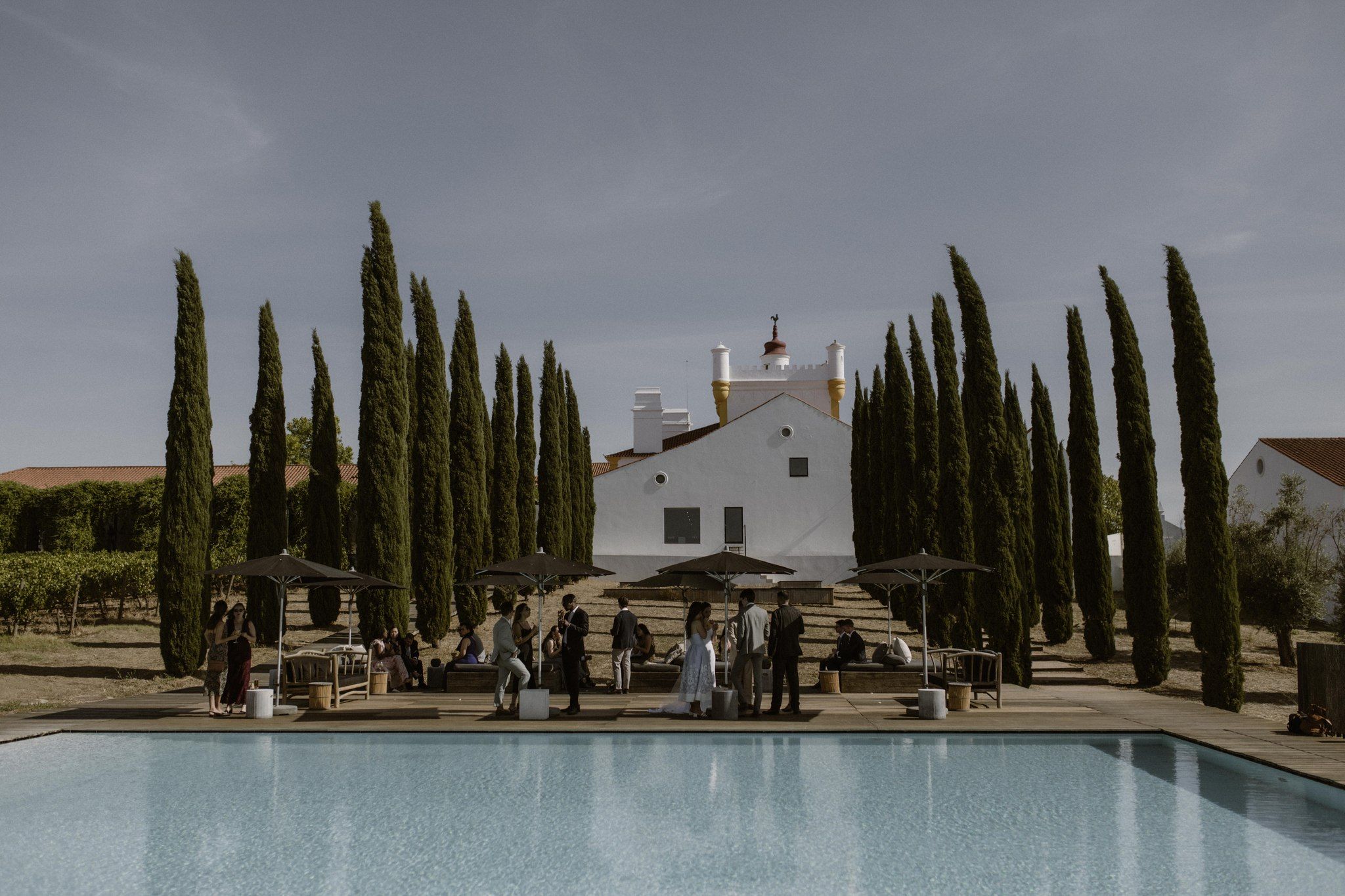 Tall cypress trees line up to frame a spacious area in front of a hotel in Alentejo during a small wedding in Portugal