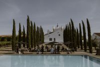 Tall cypress trees line up to frame a spacious area in front of a hotel in Alentejo during a small wedding in Portugal