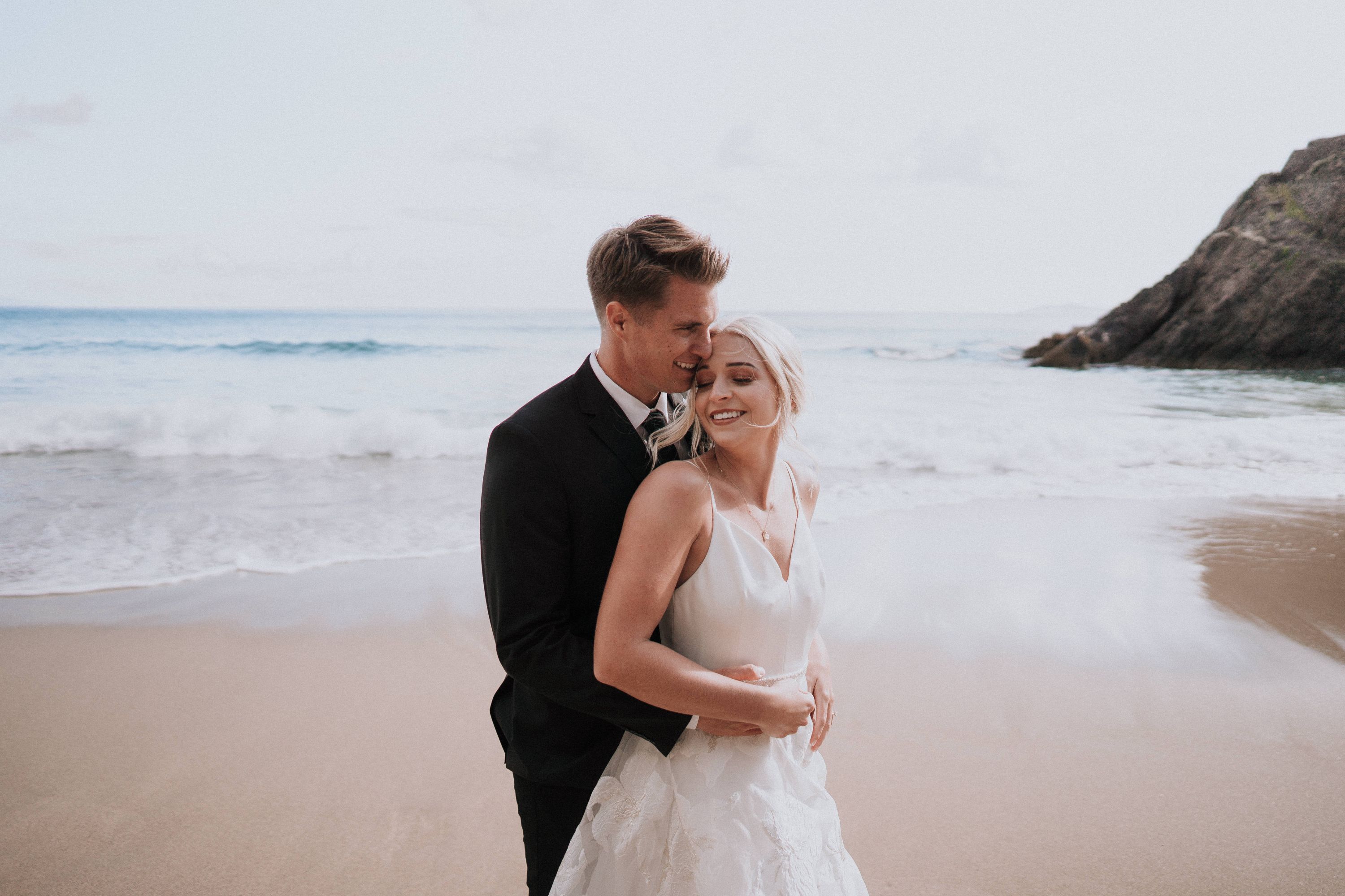 Bride and groom in front of their celebrant, holding hands under a white garden gazebo, having a wedding ceremony in Portugal