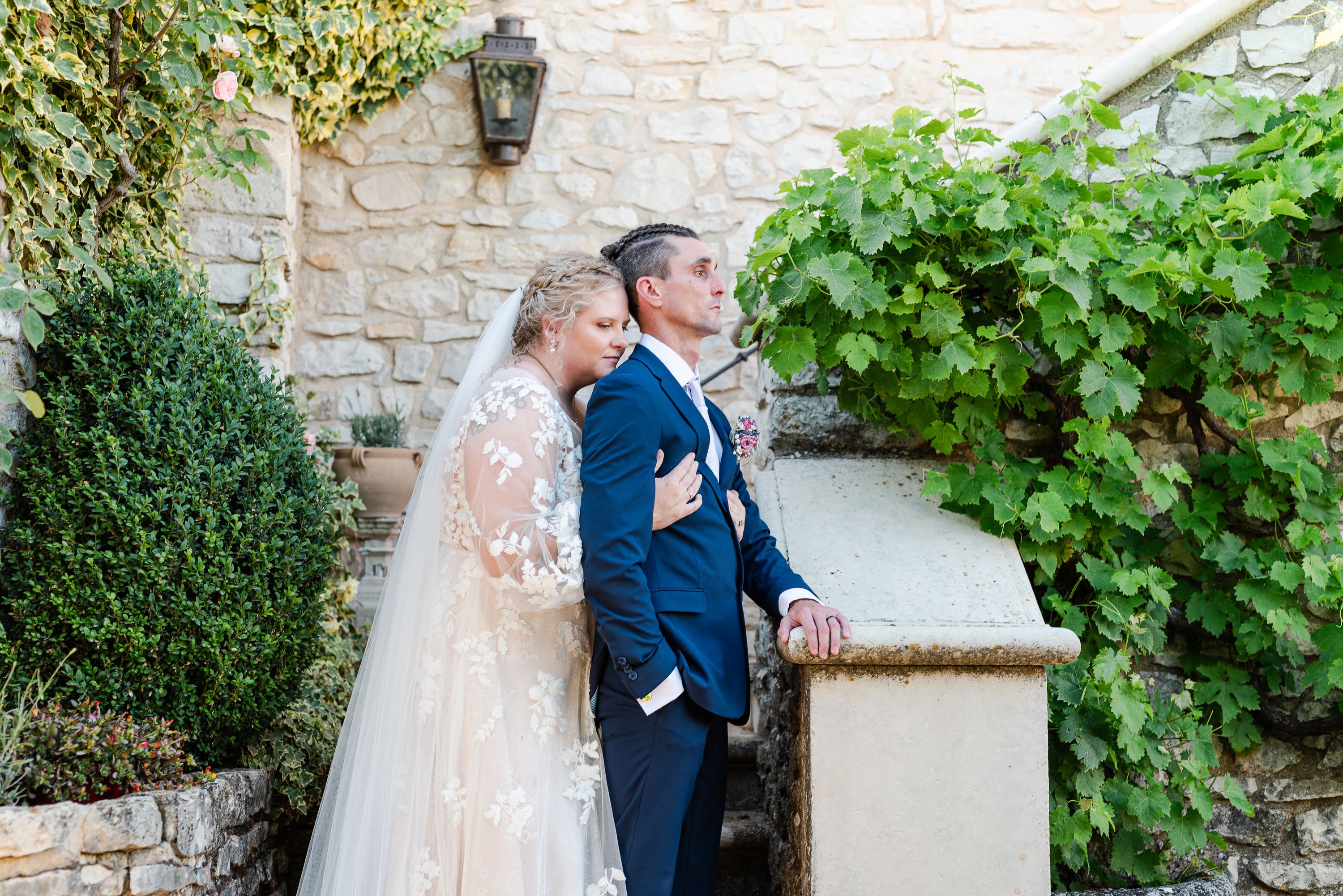 Bride and groom embrace in a stone courtyard garden during an intimate wedding in France