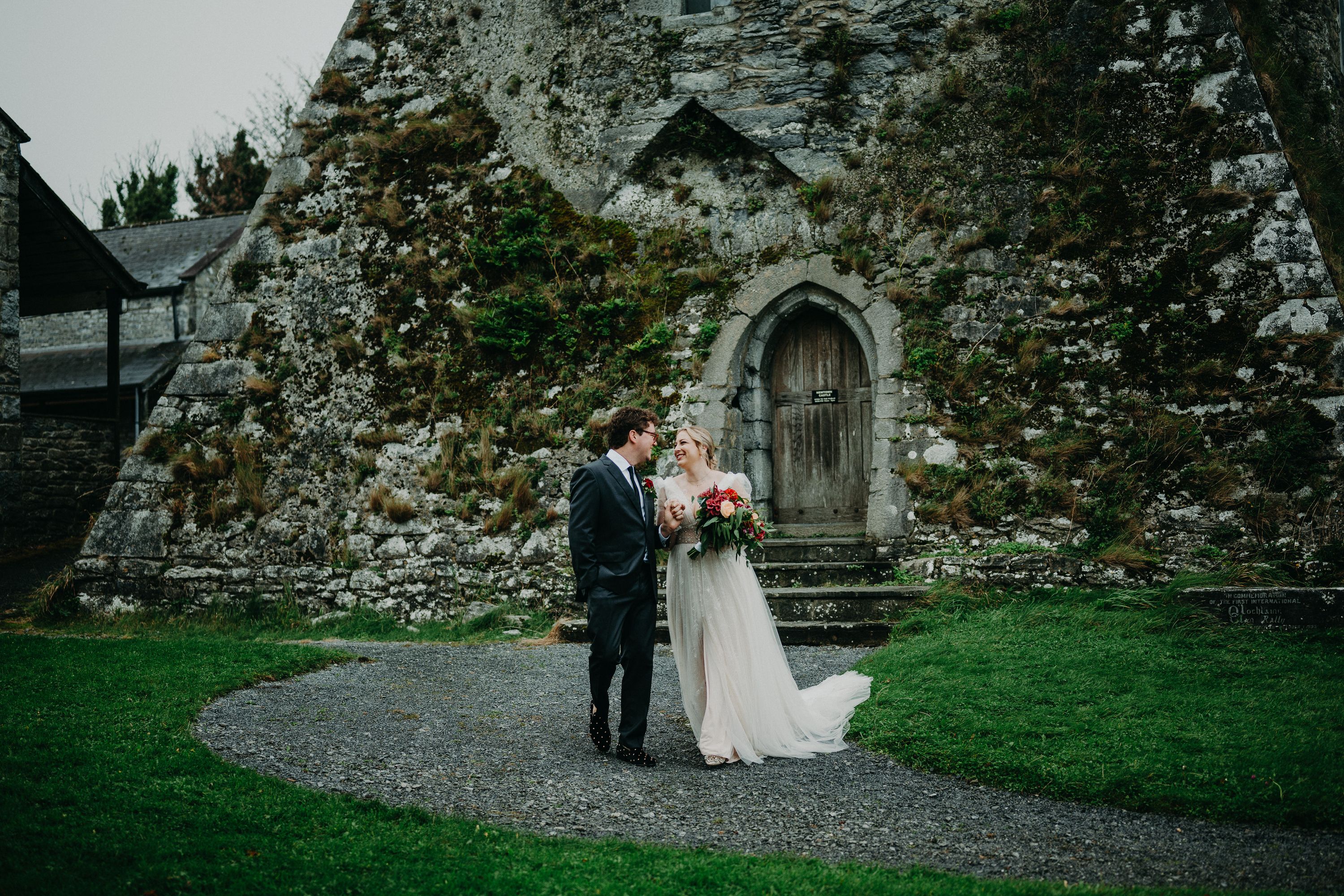 Bride and groom smiling beneath a medieval tower during an intimate wedding in Ireland with castle charm