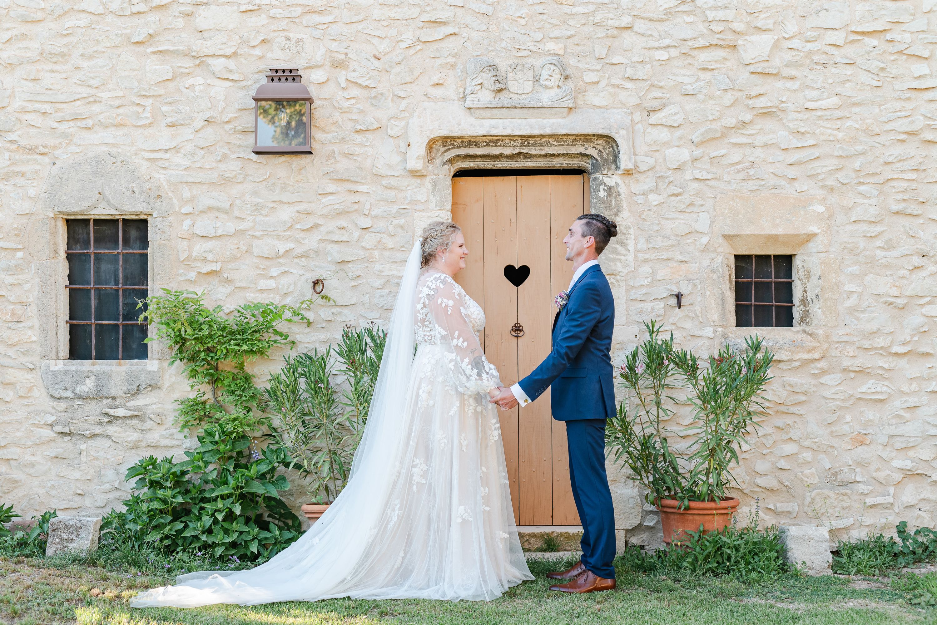Bride and groom holding hands in front of a rustic stone cottage at an intimate wedding in France