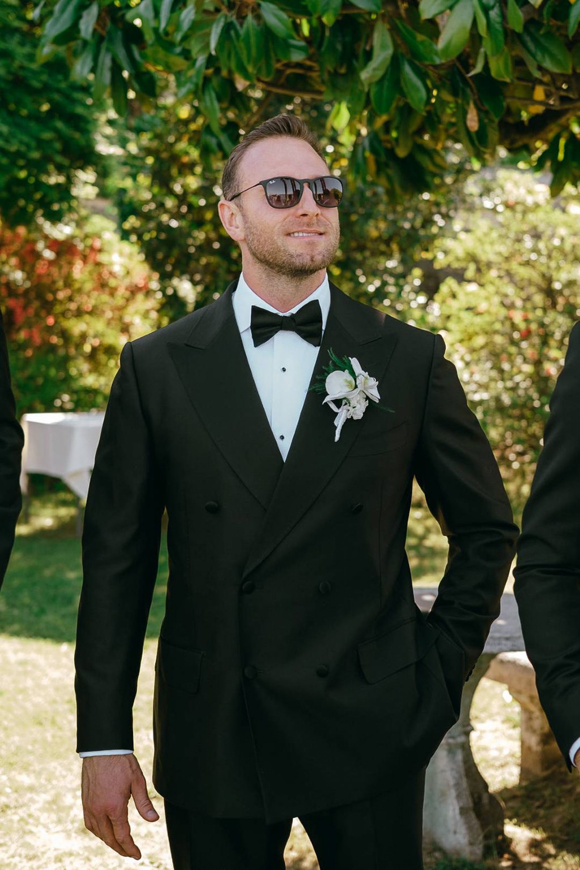 Groom in a classic black tuxedo outdoors before a small wedding in Italy surrounded by lush greenery