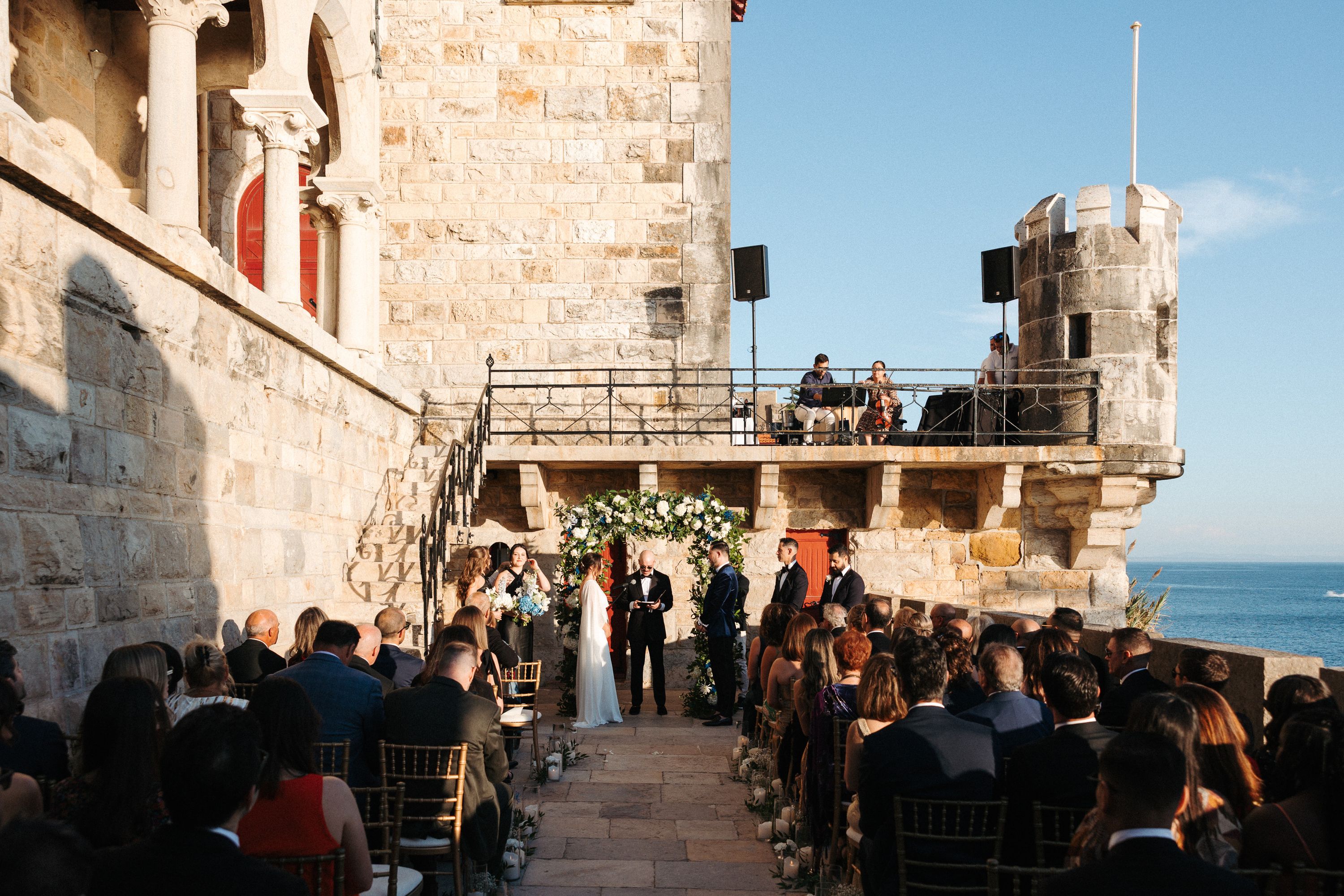 Couple exchanging vows at a coastal castle venue during an intimate wedding in Portugal overlooking the Atlantic Ocean