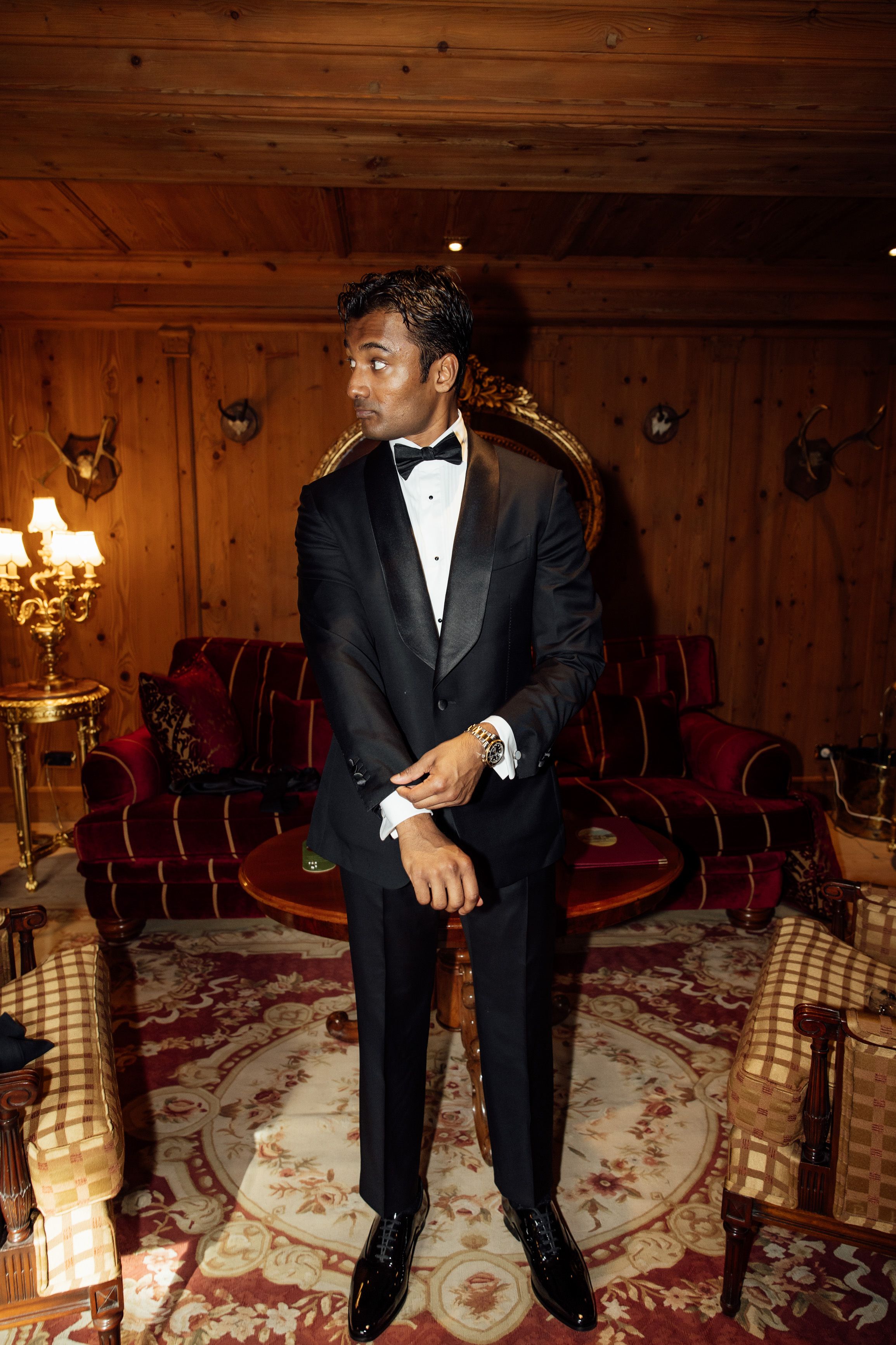 Groom in a black tuxedo getting ready inside a traditional lodge for a small wedding in Austria