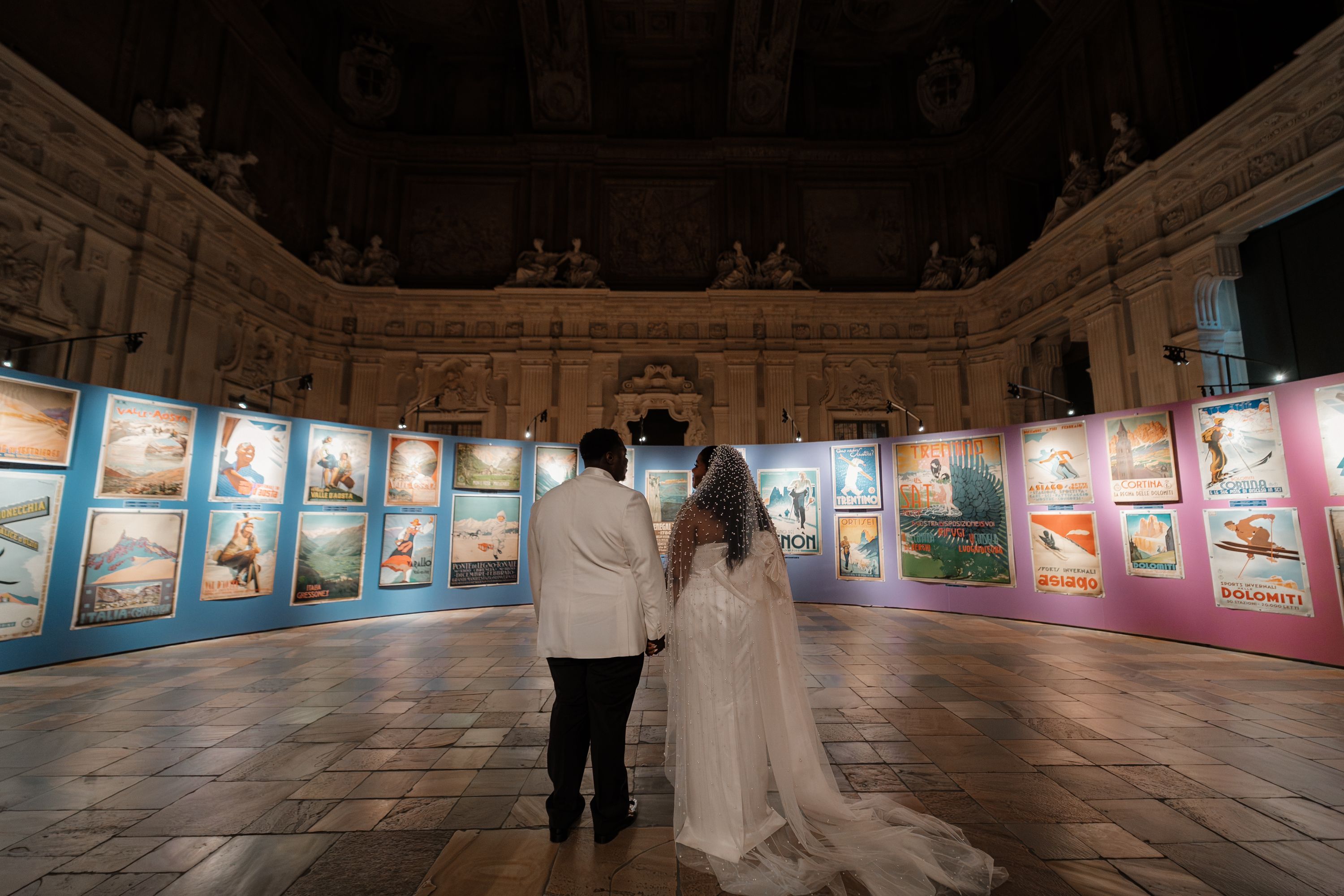 Bride and groom with backs behind the camera looking at an art gallery in a museum during their elopement in Italy