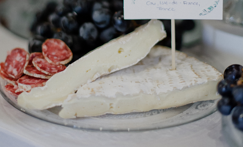 Cheese board with soft-rind cheese, salami, and grapes at a wedding reception